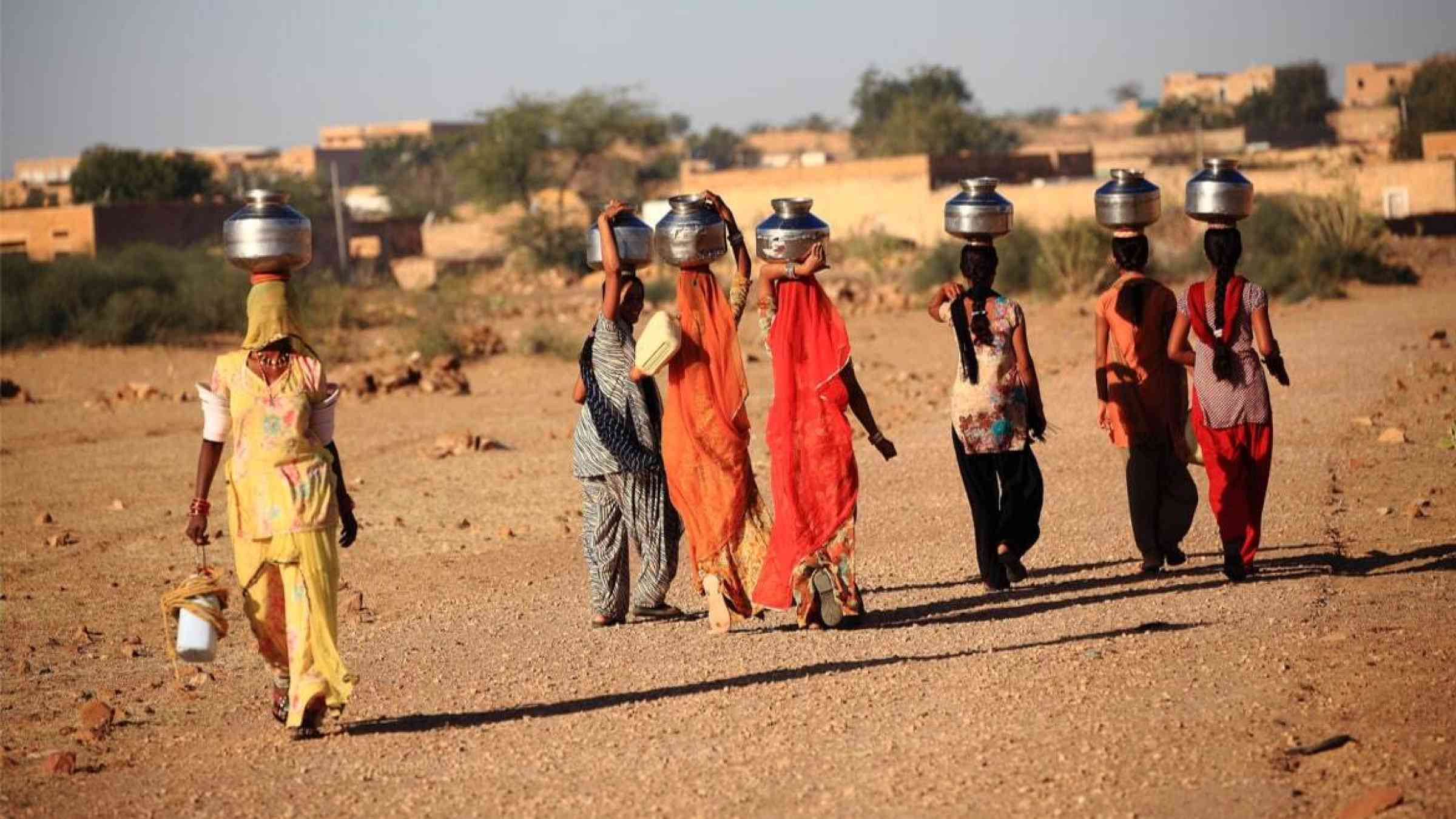 Women carrying water pots on their heads, India
