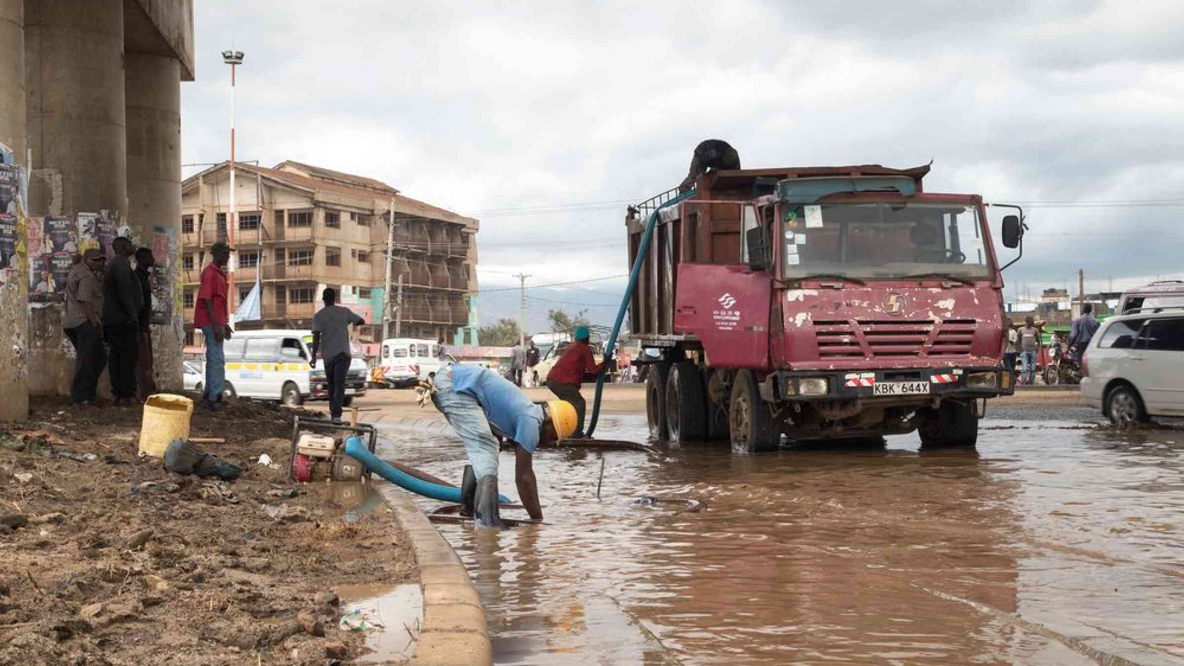 Workers drain a flooded thoroughfare after a night of severe thunderstorms in Kisumu, Kenya