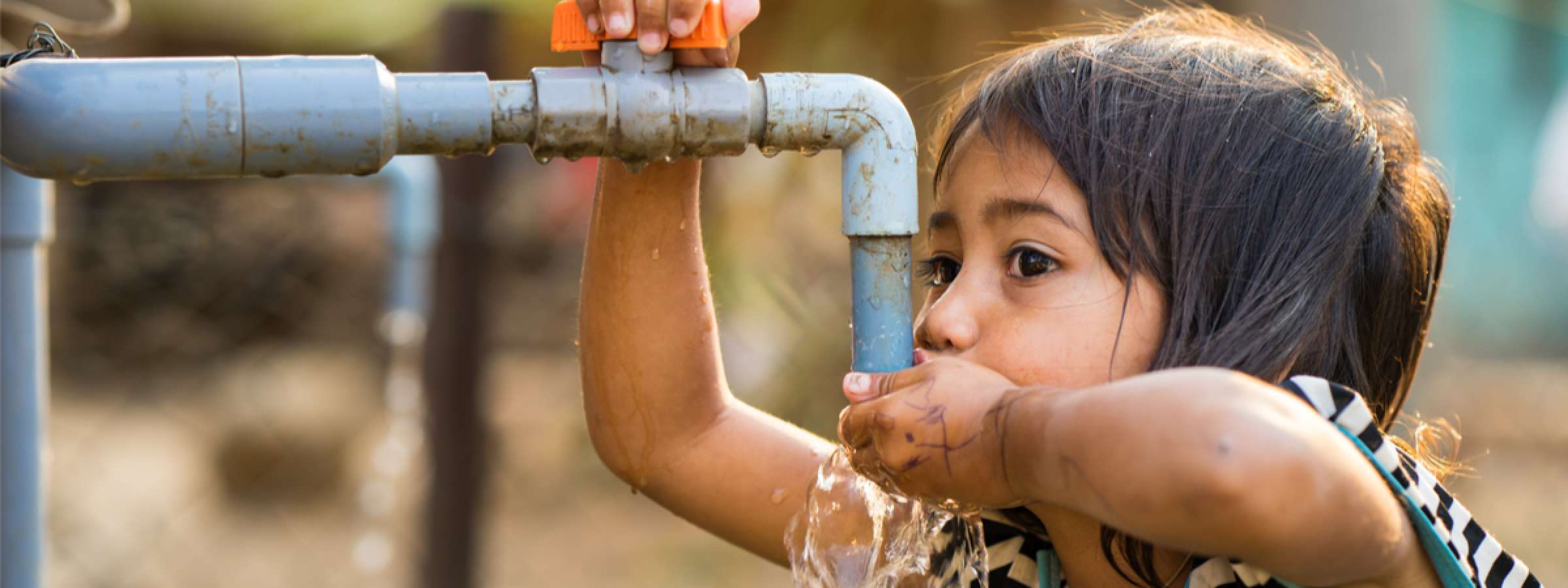  A little girl drink water from outdoor tap which water supplied by drilling well