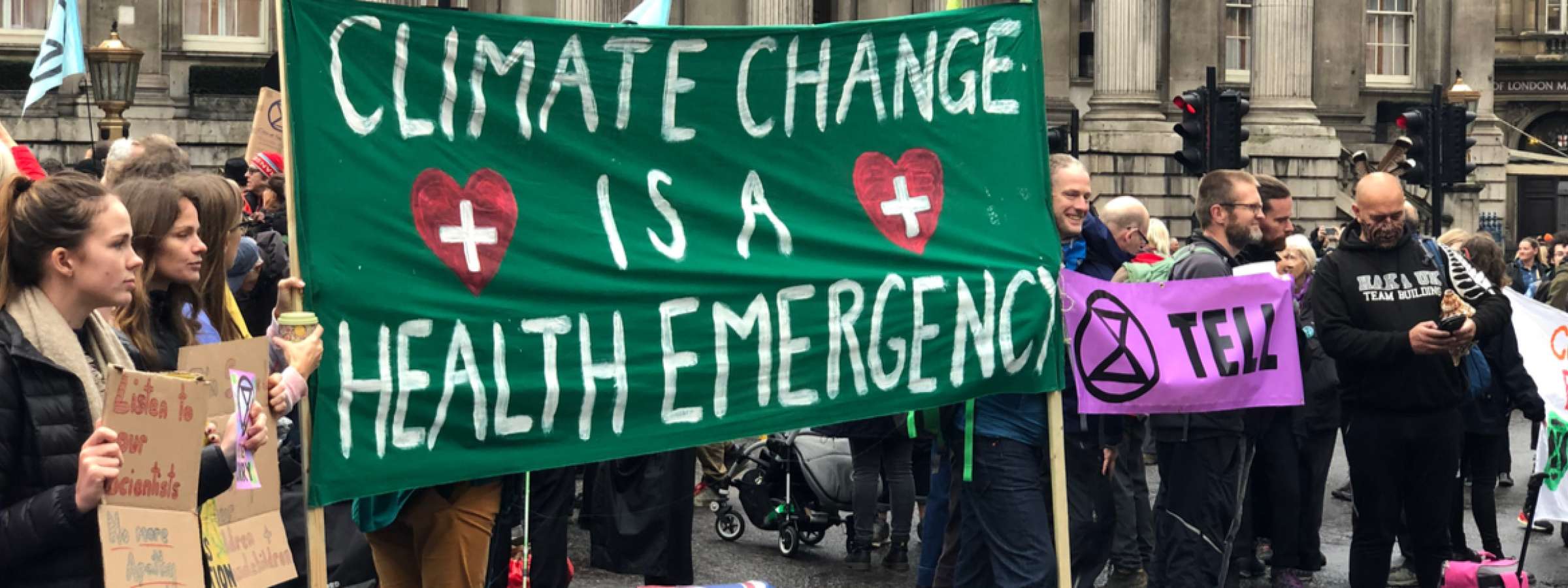 This image shows a group of people demonstrating. They are holding a large green banner that says" Climate change is a health emergency".