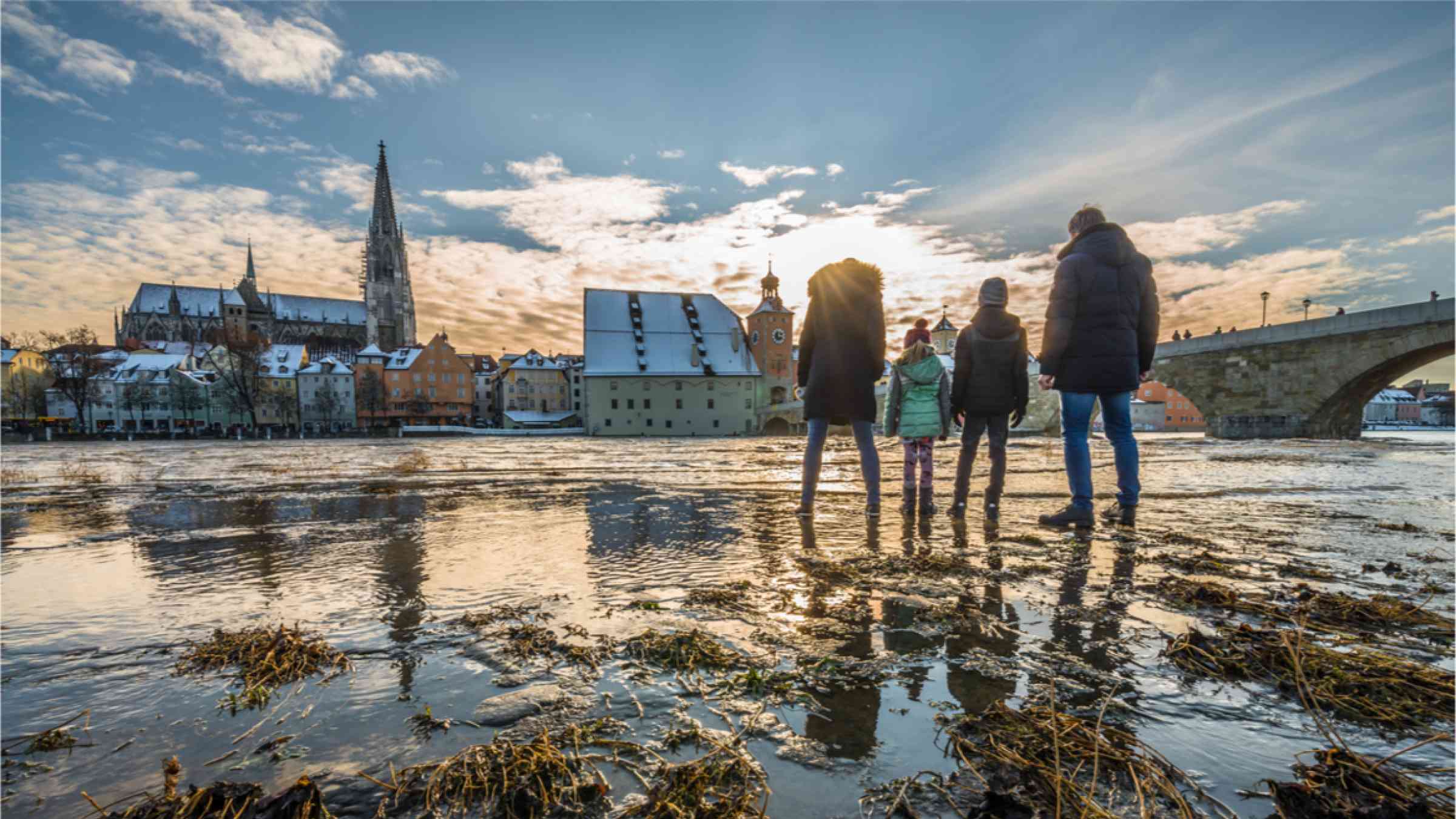 A family observes the aftermath of flooding on the banks of the Danube