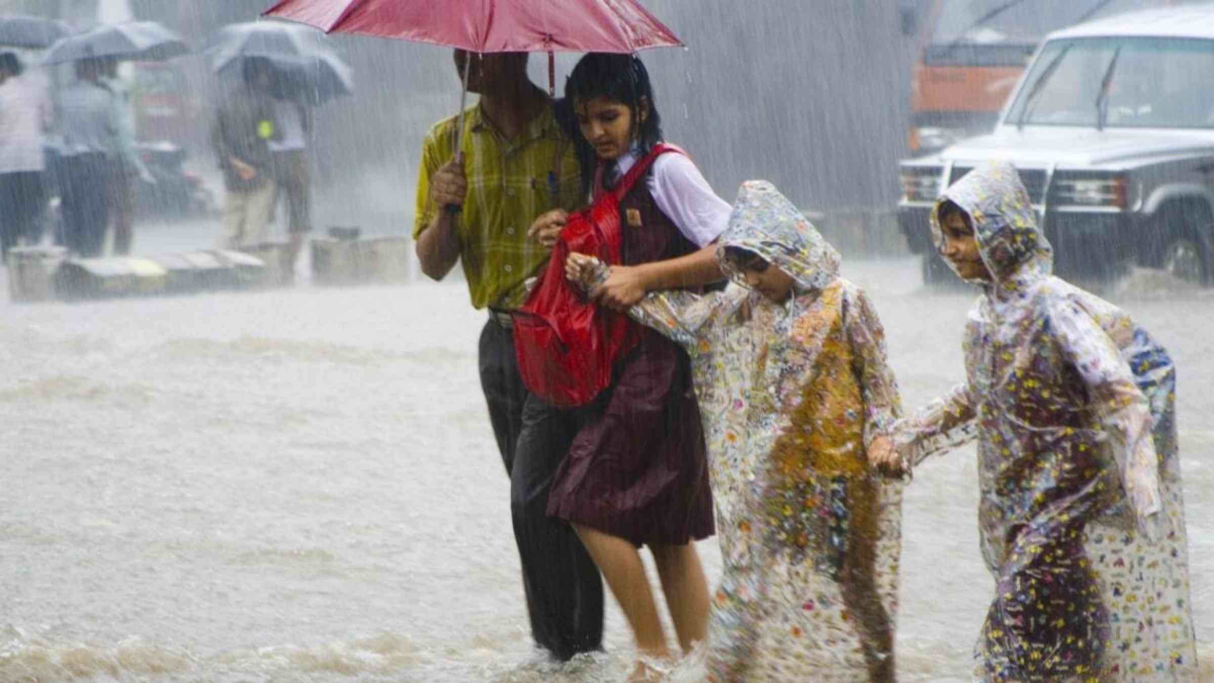 A parent accompanies three children amidst heavy rains in Mumbai, India