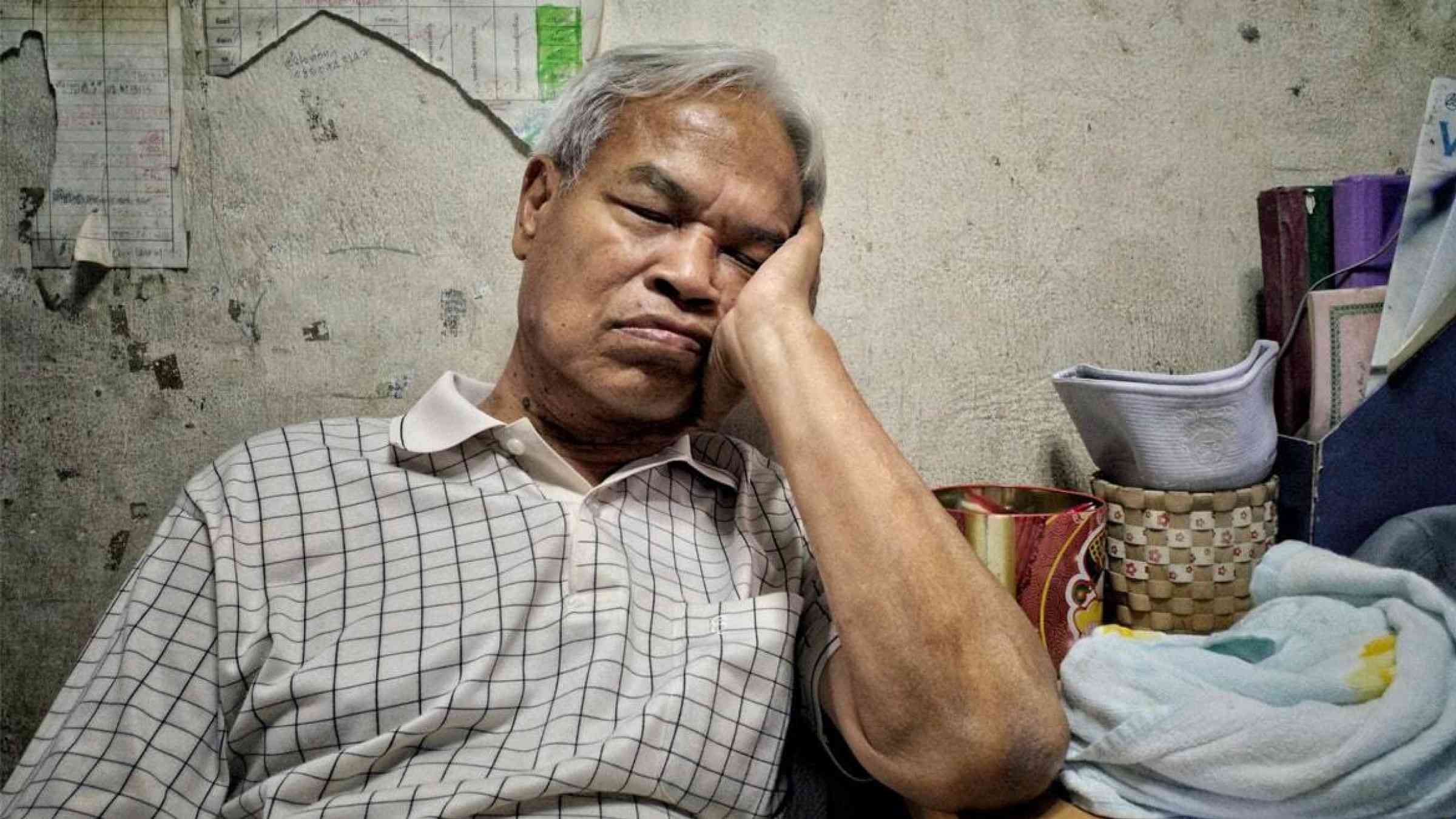 An elderly vendor in Bangkok, Thailand takes a nap