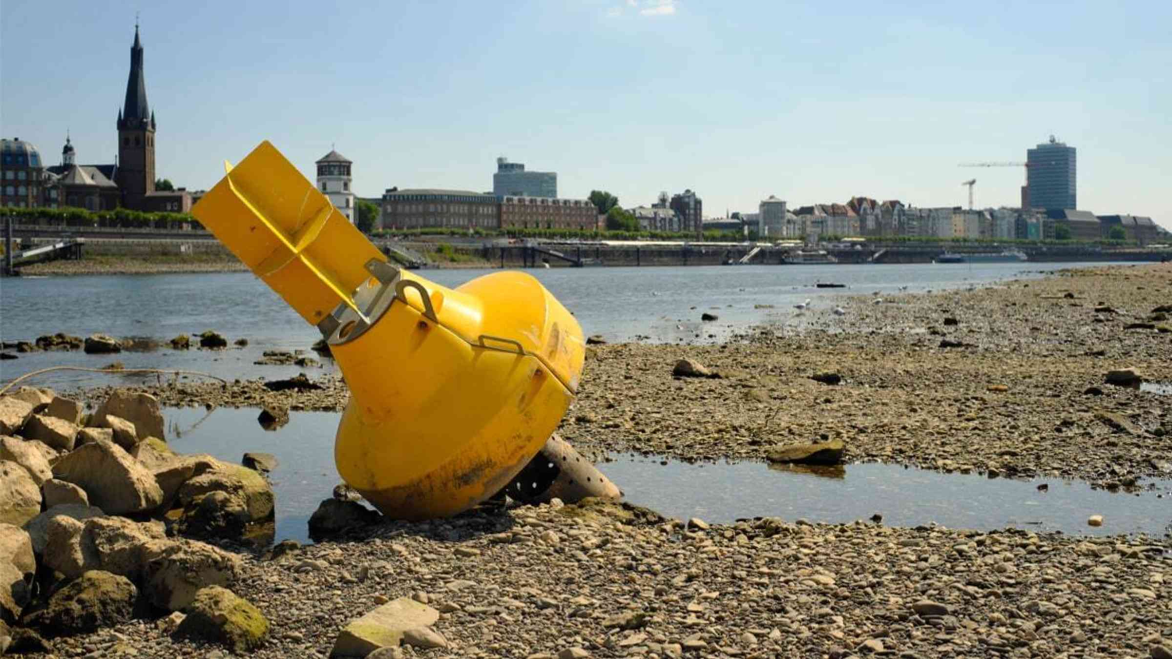 An image of a yellow buoy resting on the dried Rhine riverbed
