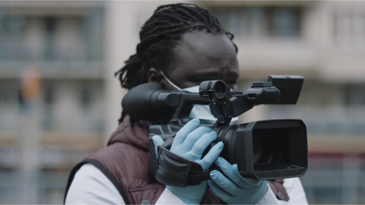 Close up of an African Black videographer looking through viewfinder on video camera.