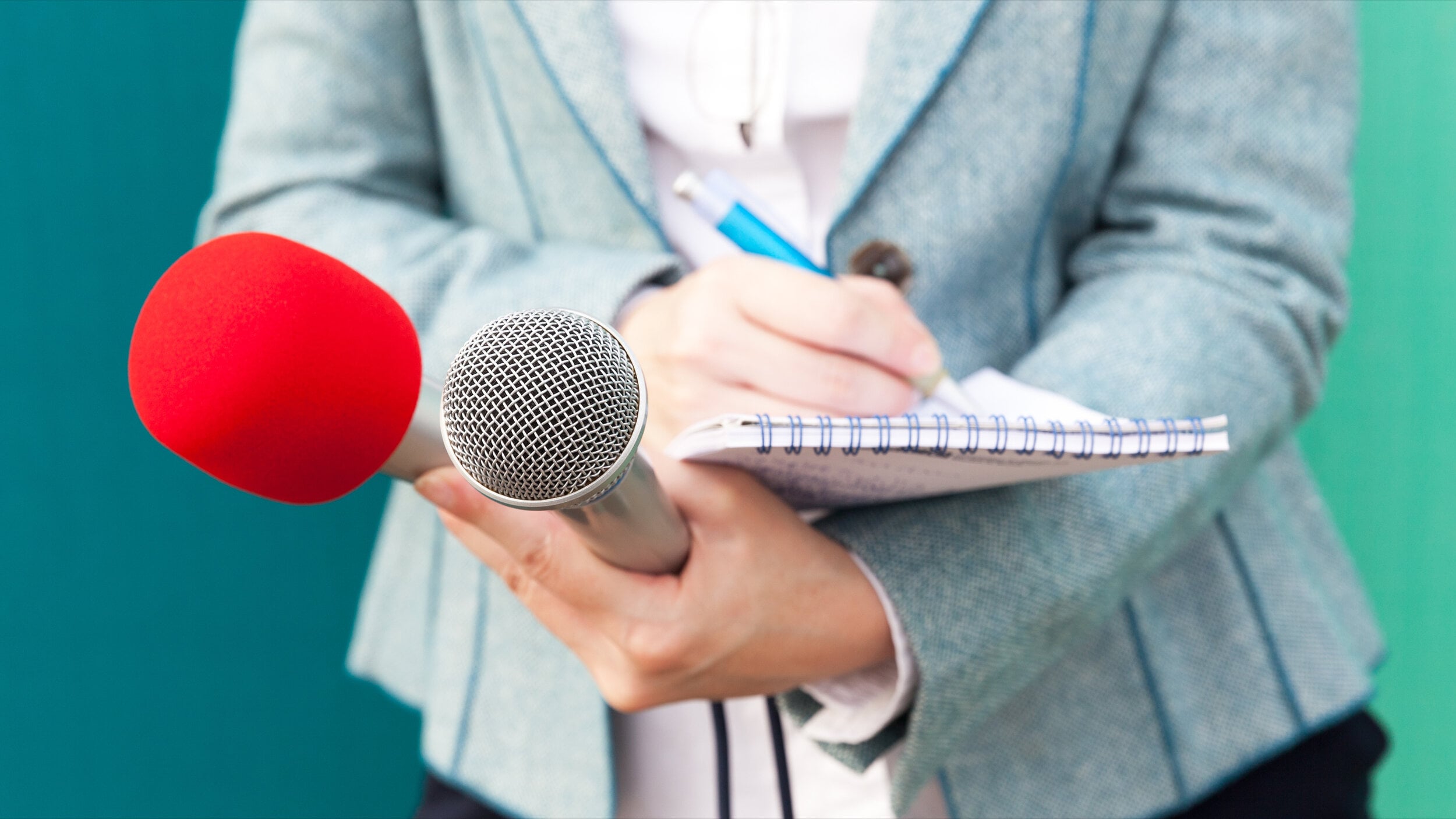 Journalist holding microphones and notepad