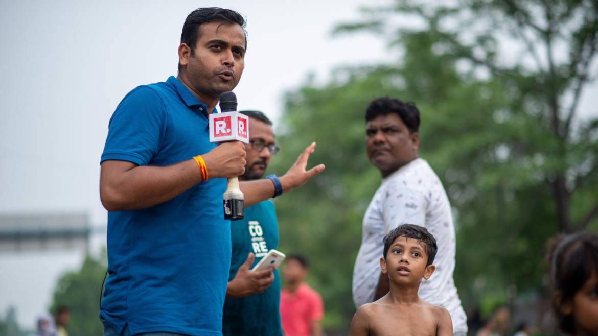 A republic tv reporter showcases the flood situation during news coverage as people swim in the floodwaters spilled onto roads surrounding Delhi's historic Red Fort.