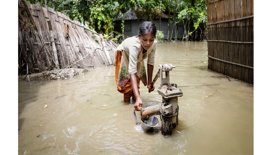 Bangladesh young girl trying to get water from a flooded water point