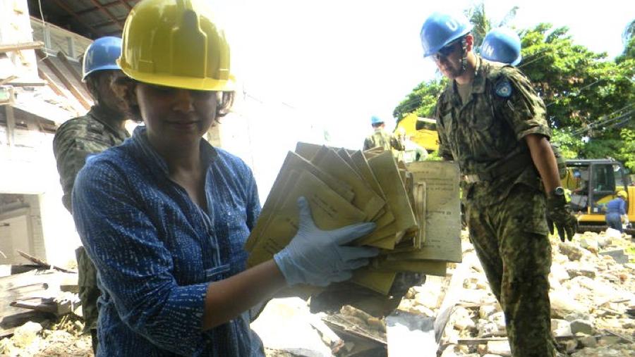 Photo: Aparna retrieving documents from debris in the Philippines.