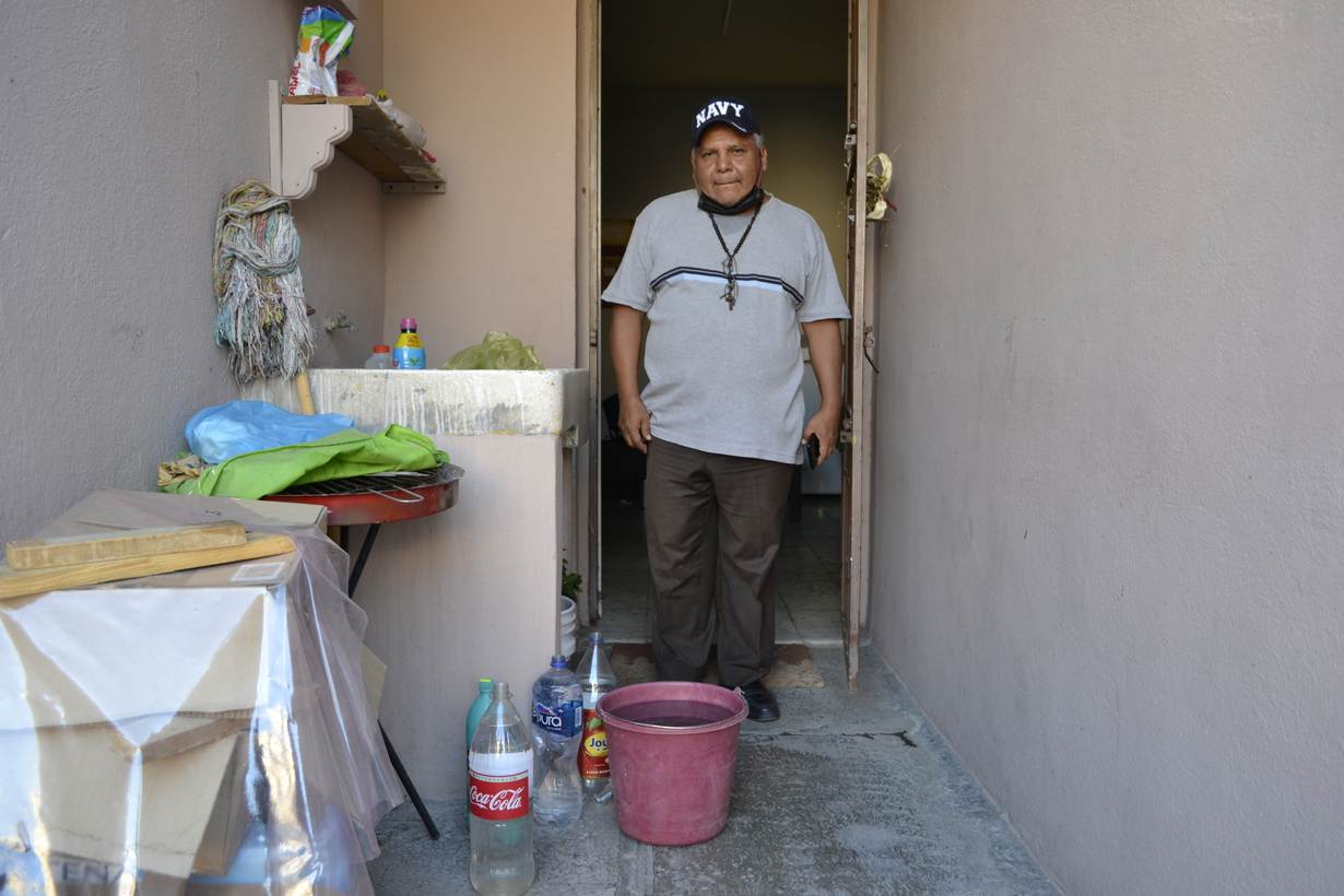Jaime Noyola poses next to the plastic containers where he collects water during the drought in Monterrey, Nuevo Leon. May 15, 2022. Thomson Reuters Foundation/Diana Baptista