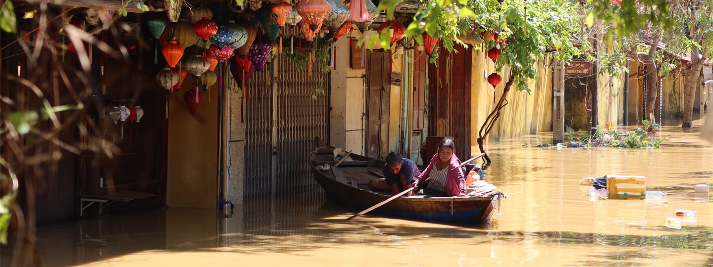 A man and a woman travel by boat through a flooded street in the city of Hoi An, Vietnam (2020)
