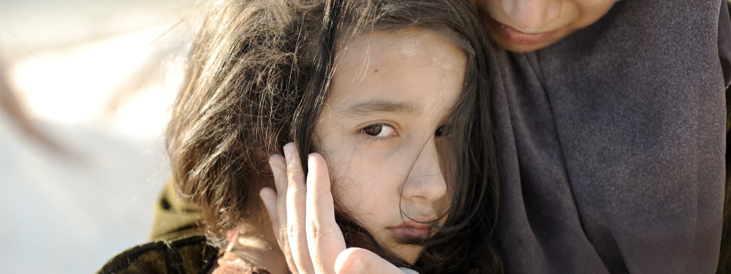 Refugee girl hugged by an older woman