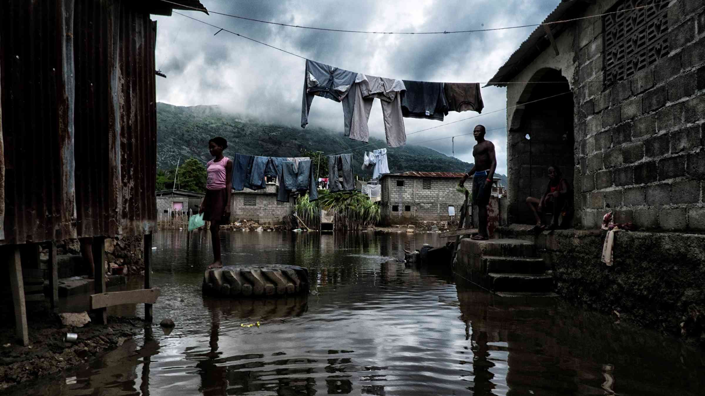 A woman looks over her flooded street in Cap Haitian