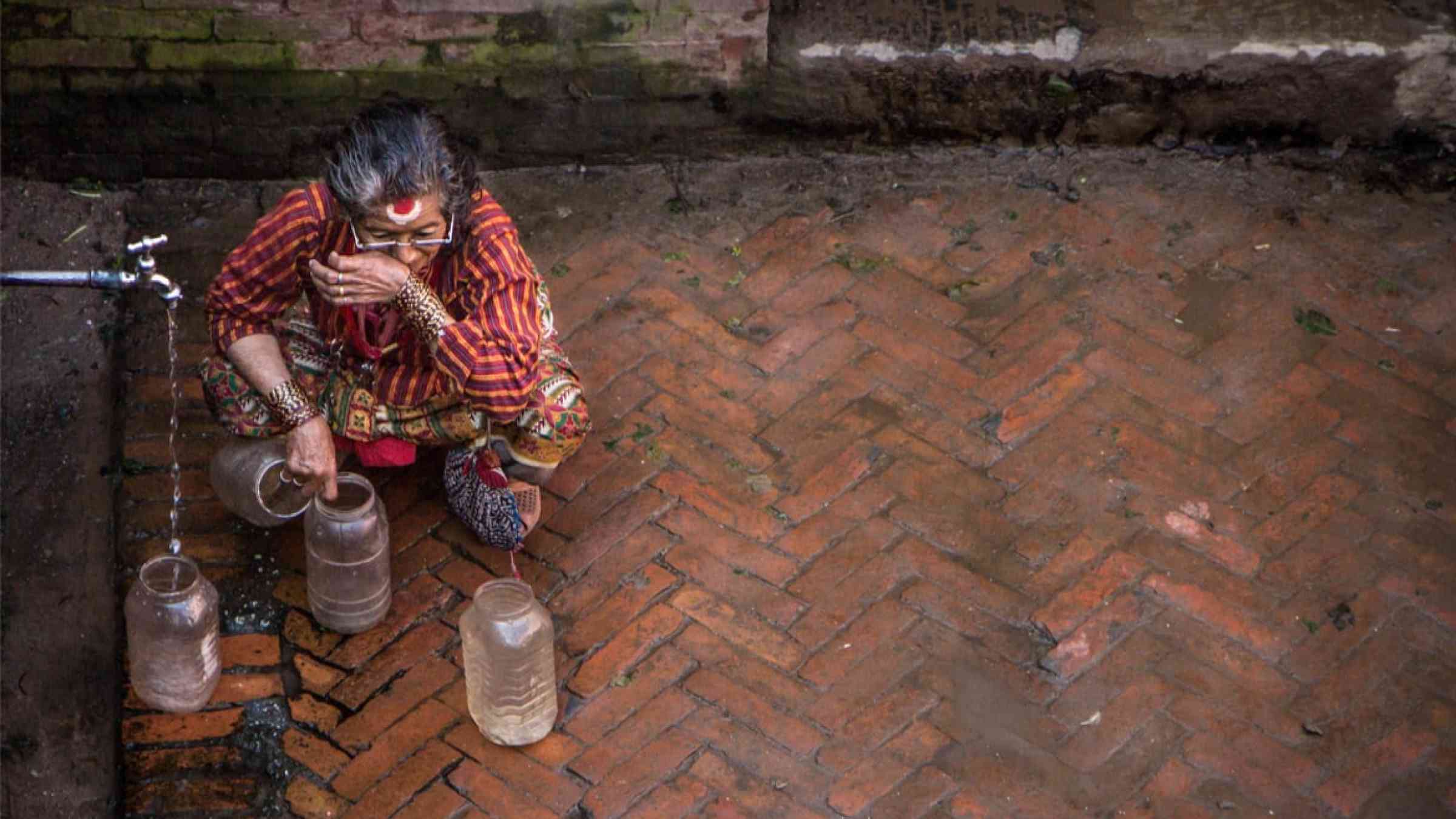 Woman collecting water from a water tap in Nepal