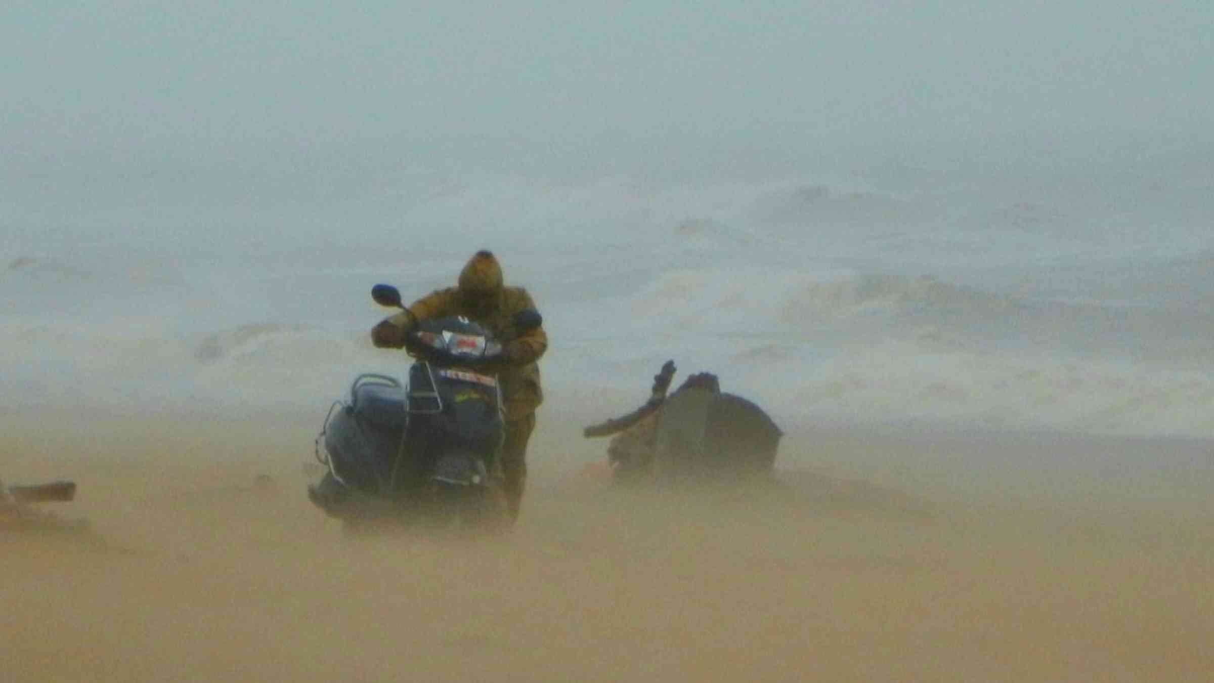 A man with his bike on the beach during Cyclone Fani, India (2019)