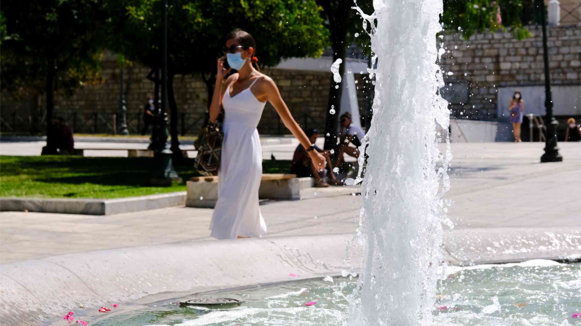 Person walks next to a fountain during a heatwave, in Athens, Greece on July 16, 2021.