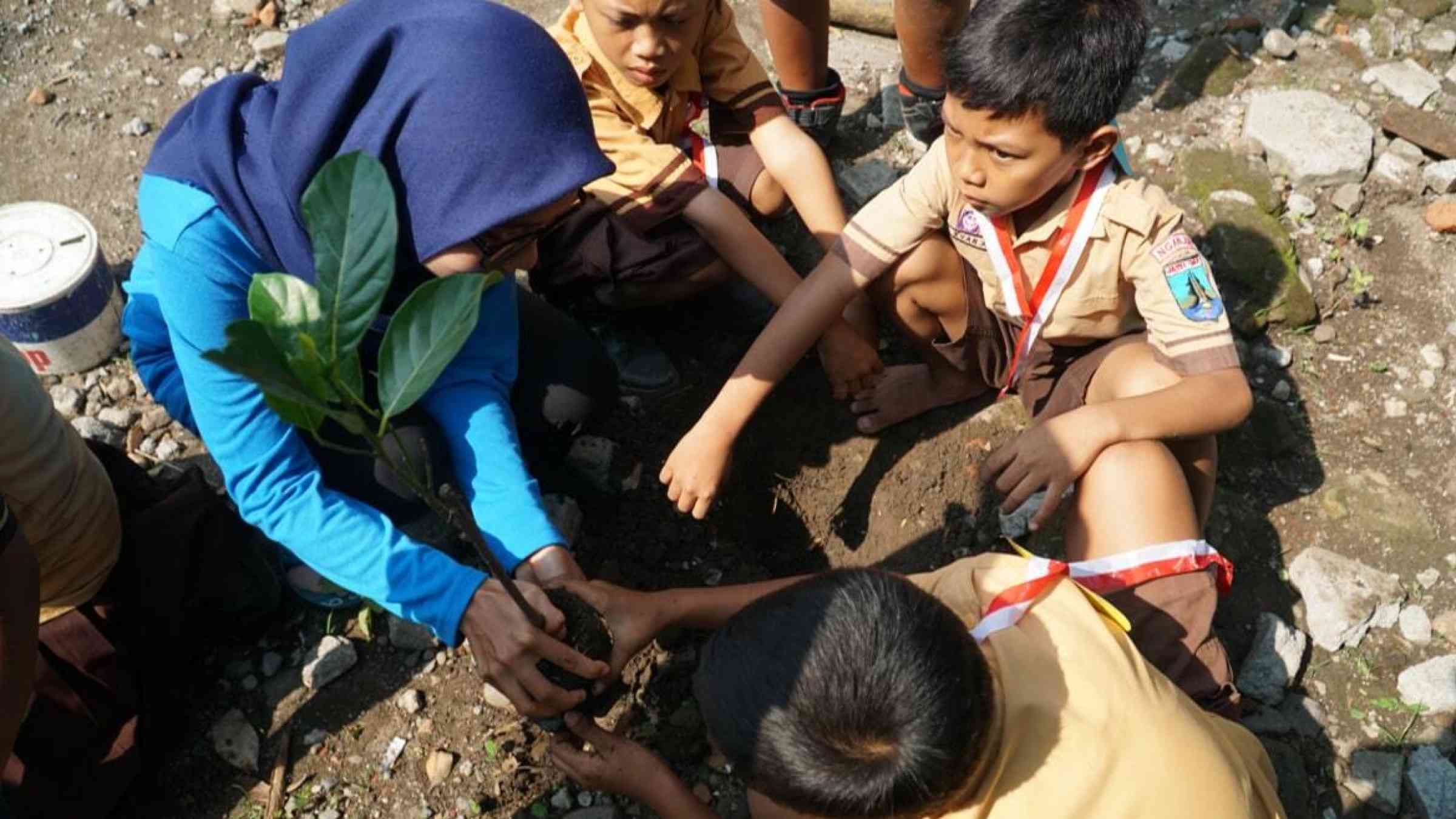 A teacher and schoolchildren plant seedlings in Kediri, Indonesia
