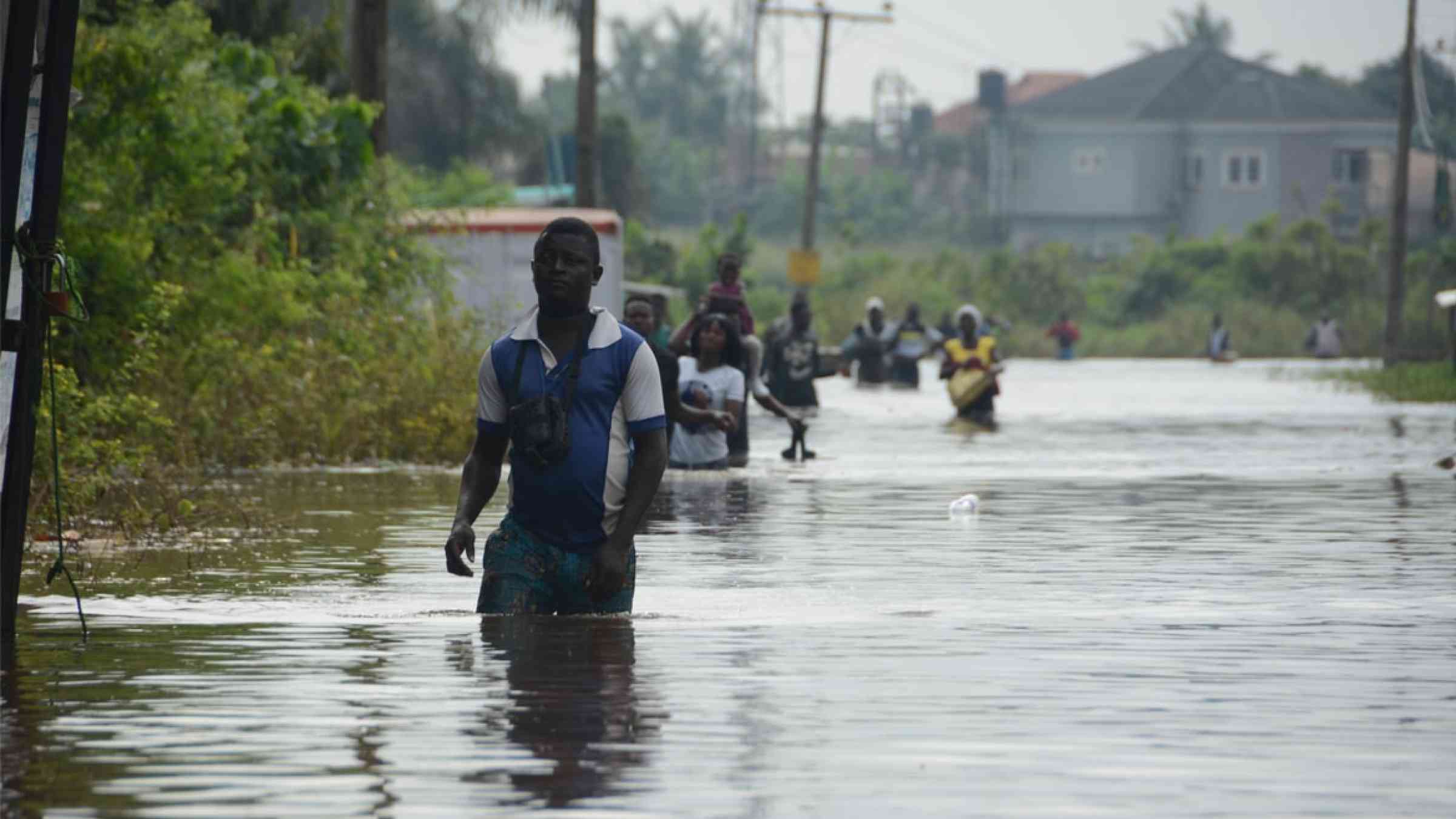 A man walks through a flash flood in Wawa, Nigeria (2019)