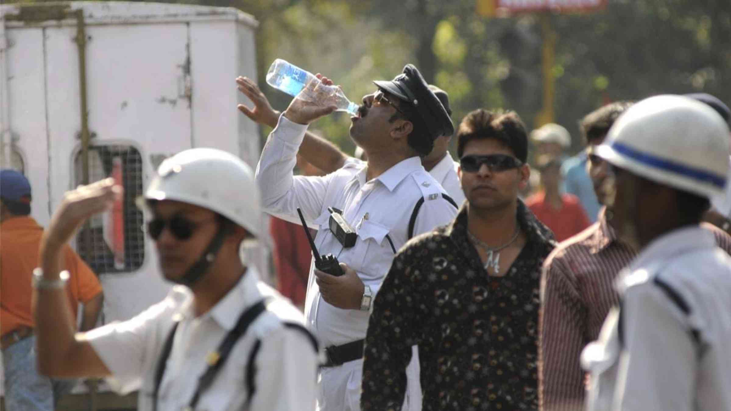 A traffic officer drinks water during a hot day in Kolkata, India