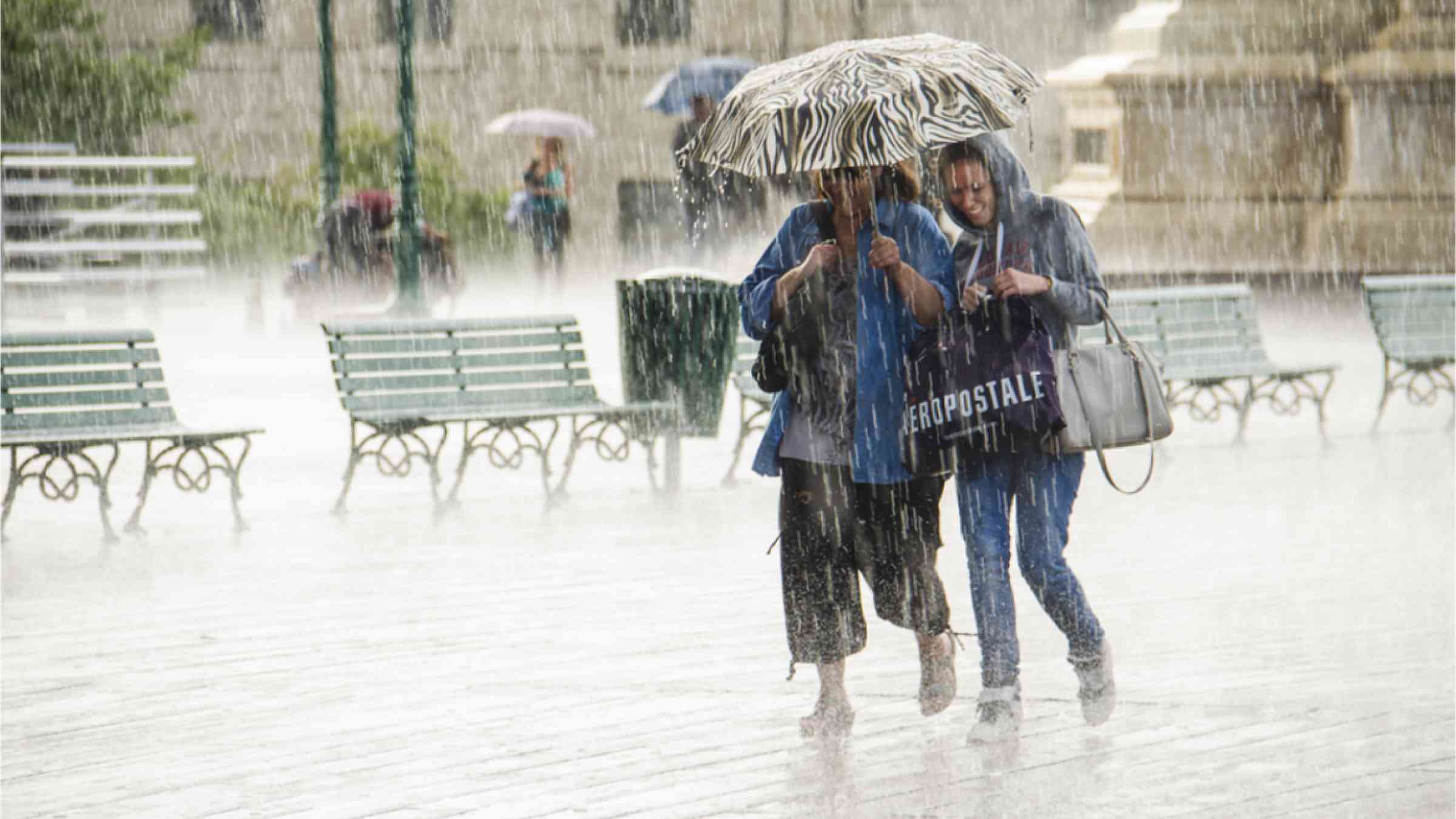 Pedestrians shelter under an umbrella amid heavy rains