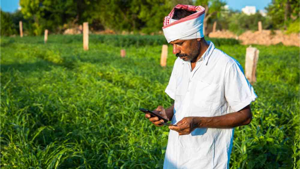 An Indian farmer processes payments through his mobile phone