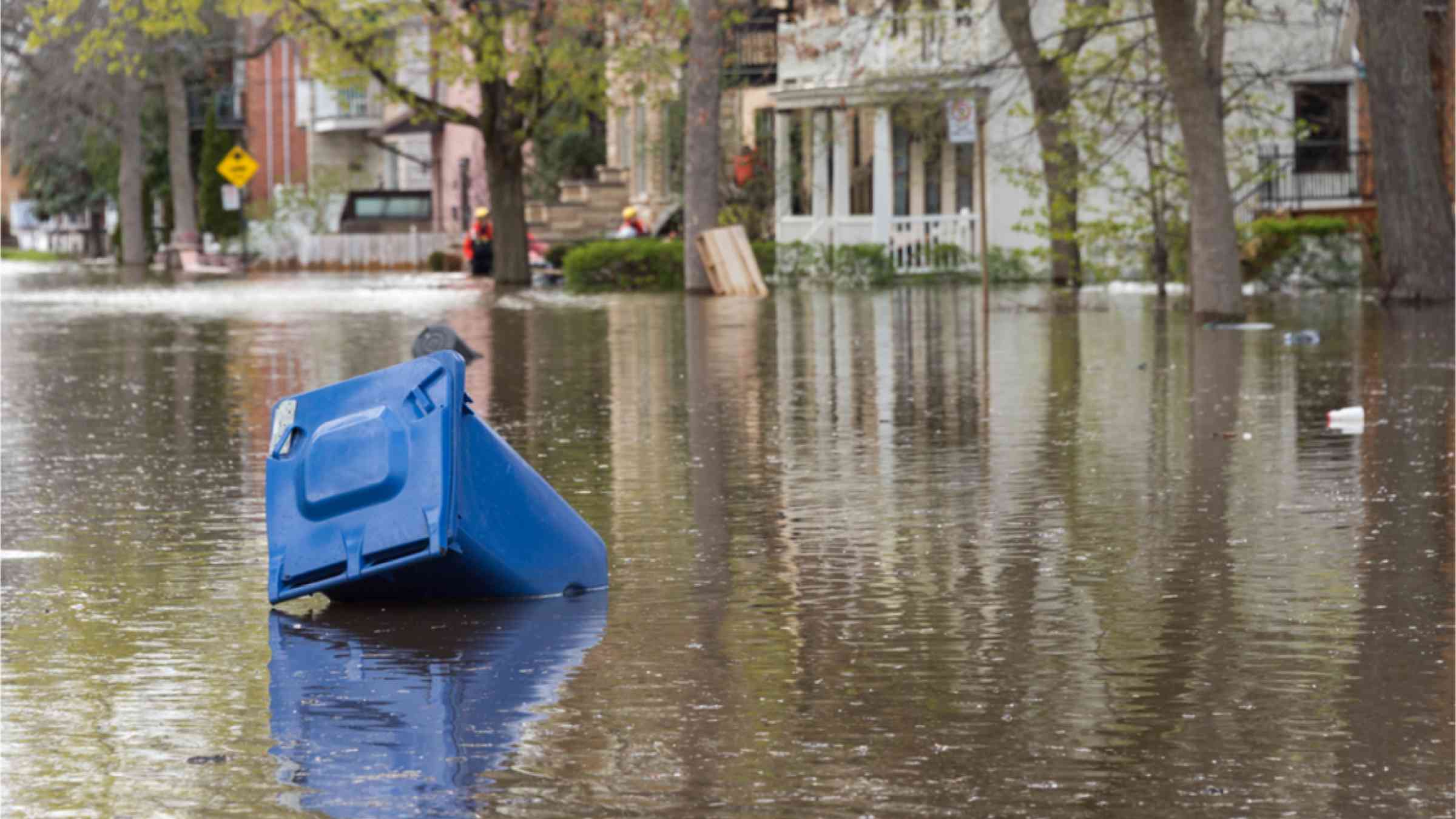 A blue bin floating on water during flooding in Montreal