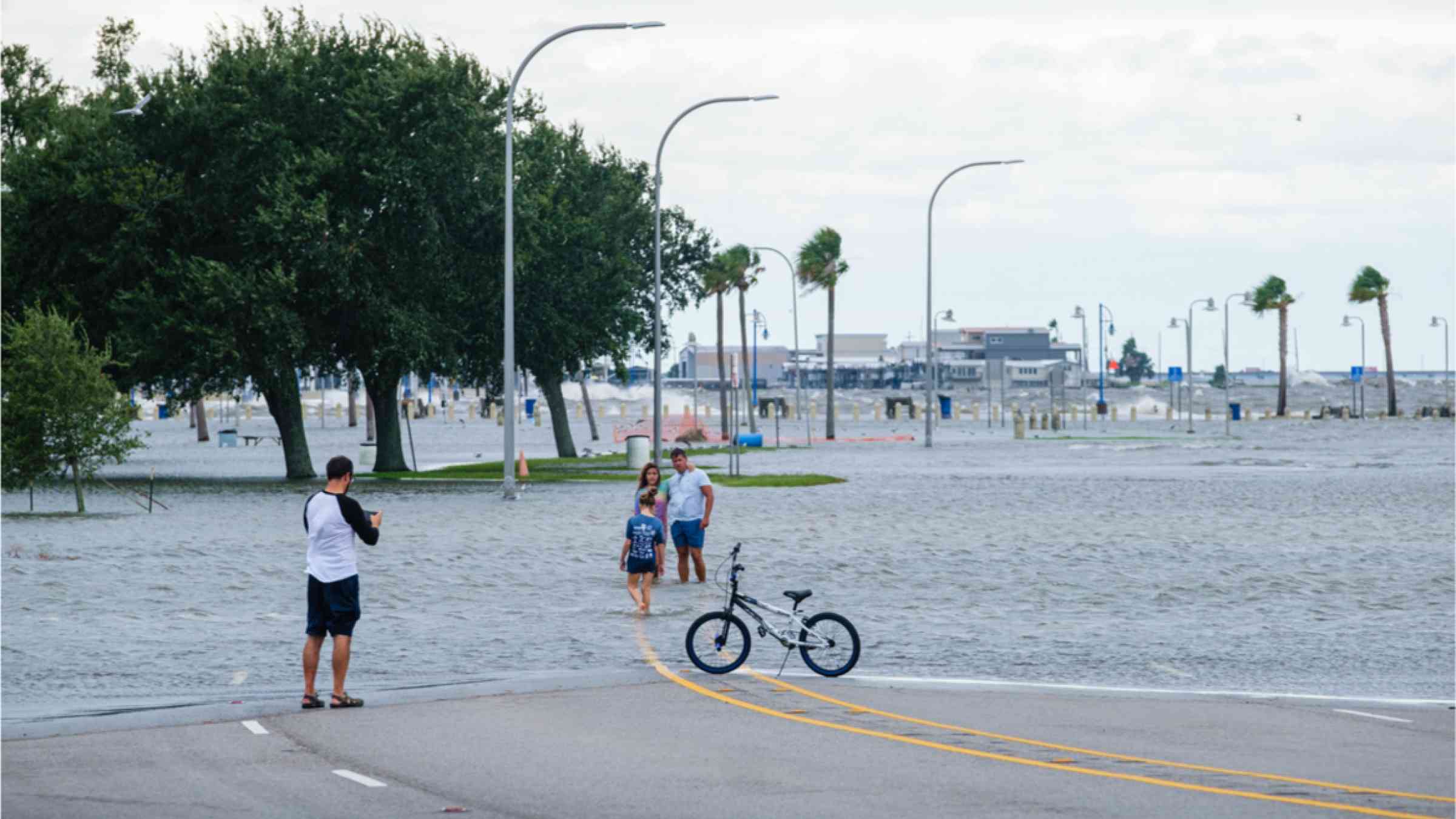 Family posing for photos amidst flooding and storm surge from Hurricane Sally along Lake Pontchartrain