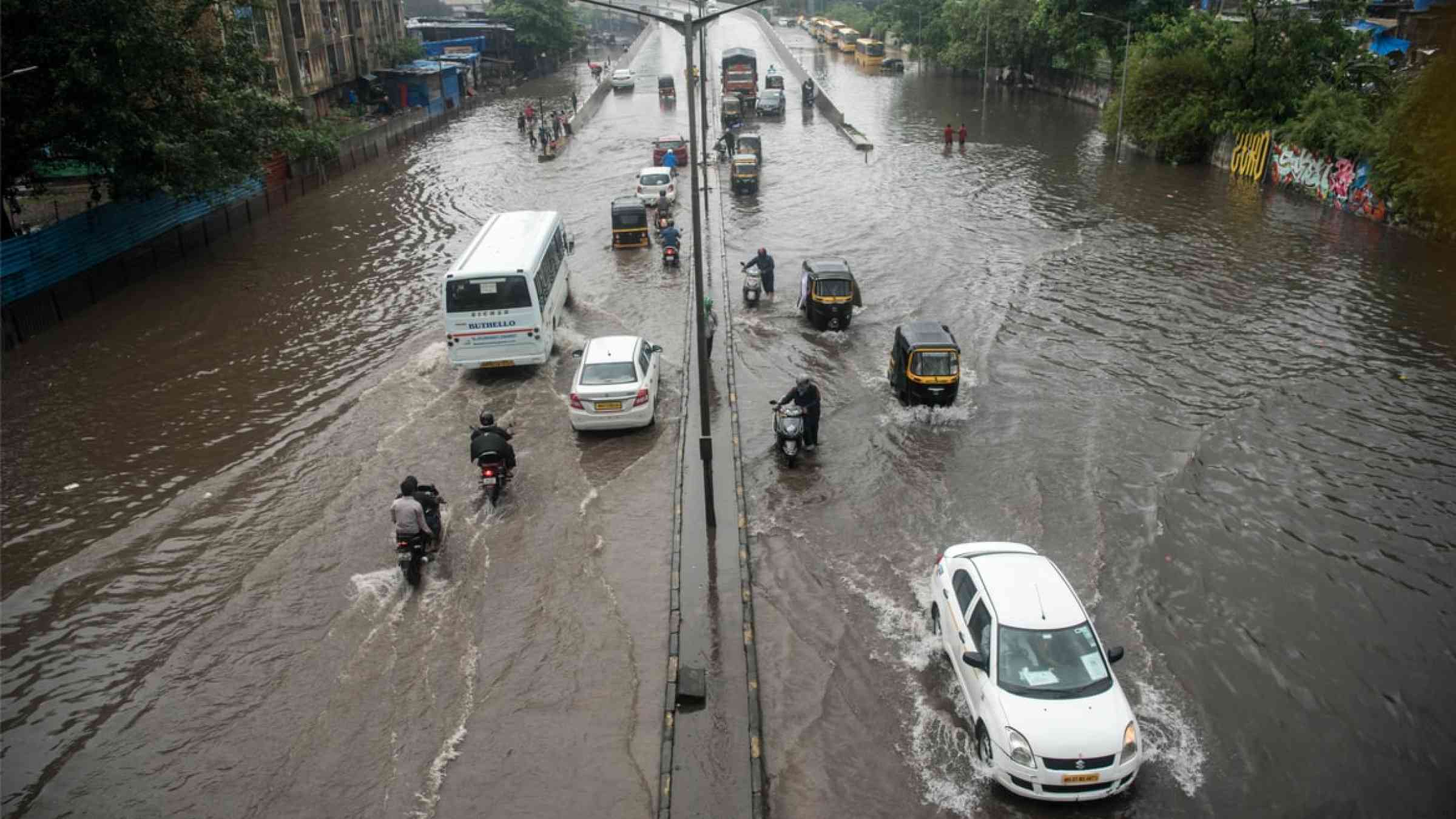 Commuters drive through a flooded street during heavy rains in Mumbai, India (2020)