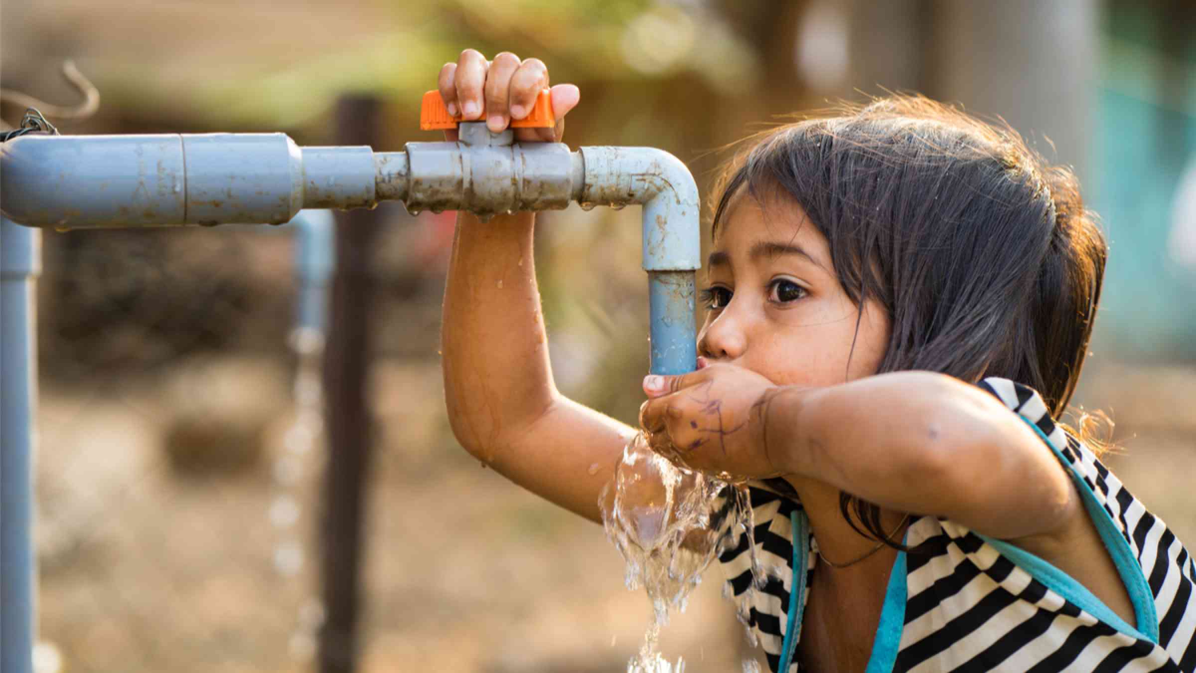  A little girl drink water from outdoor tap which water supplied by drilling well