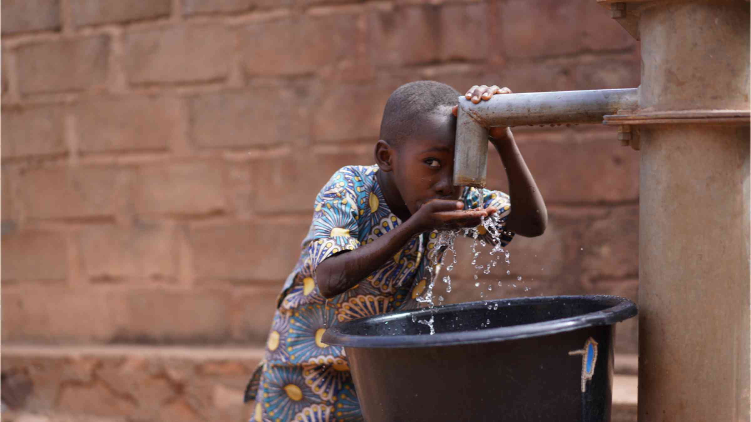 Little African Boy At The Community Borehole Quenching His Thirst