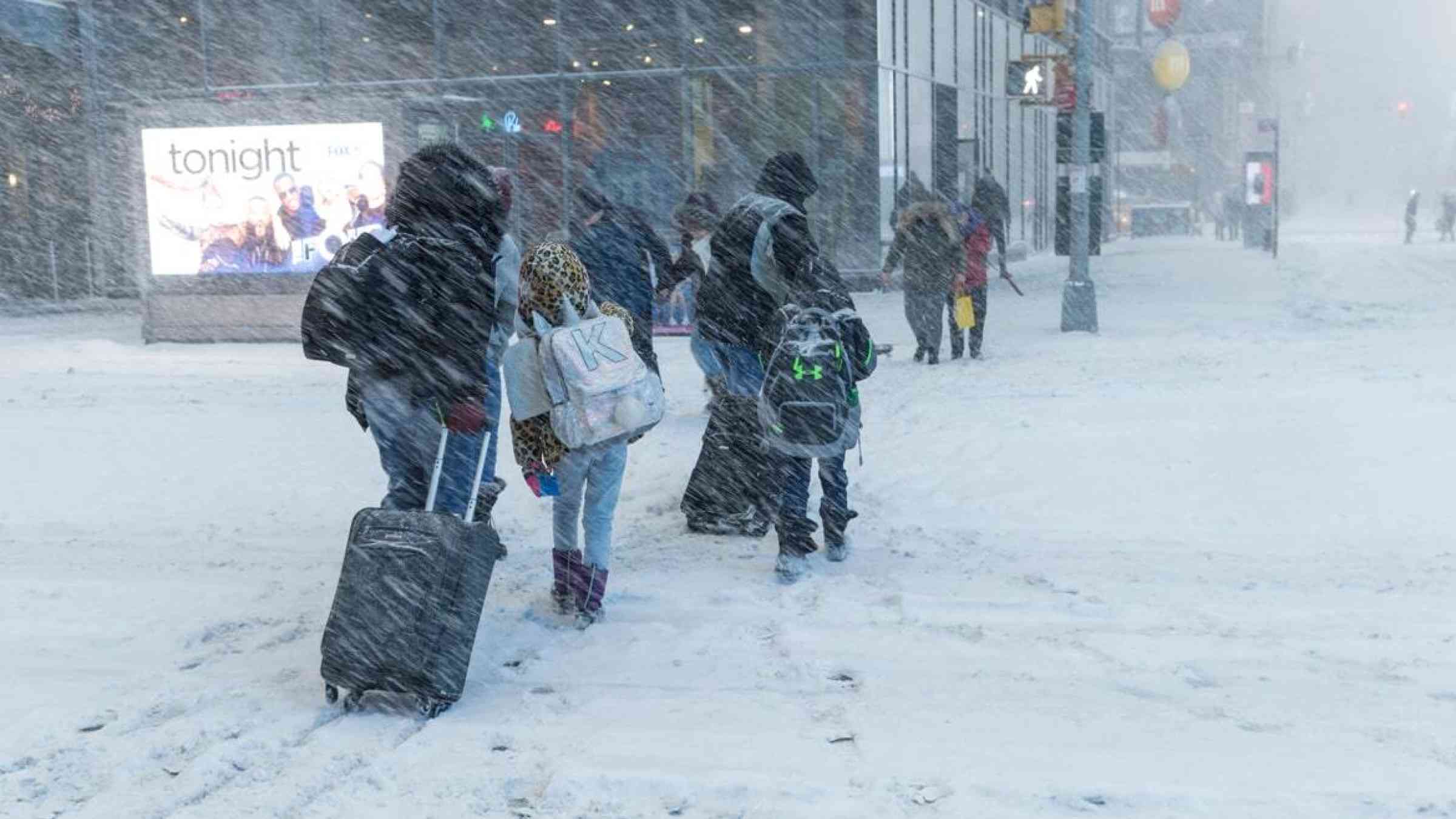 Pedestrians cross a snow-covered street during a blizzard in New York