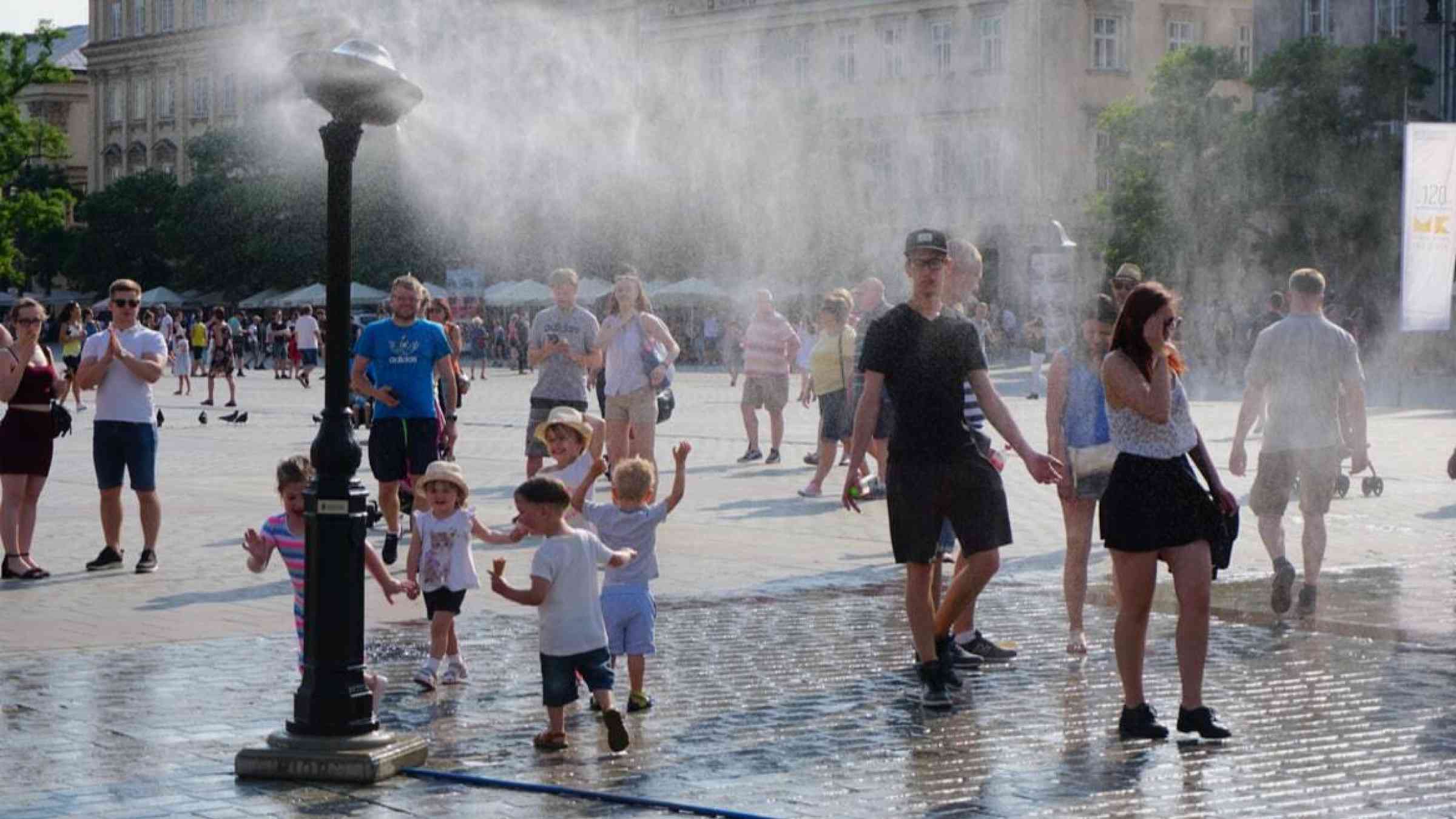 Crowds pass by a fountain during a hot day in Krakow, Poland