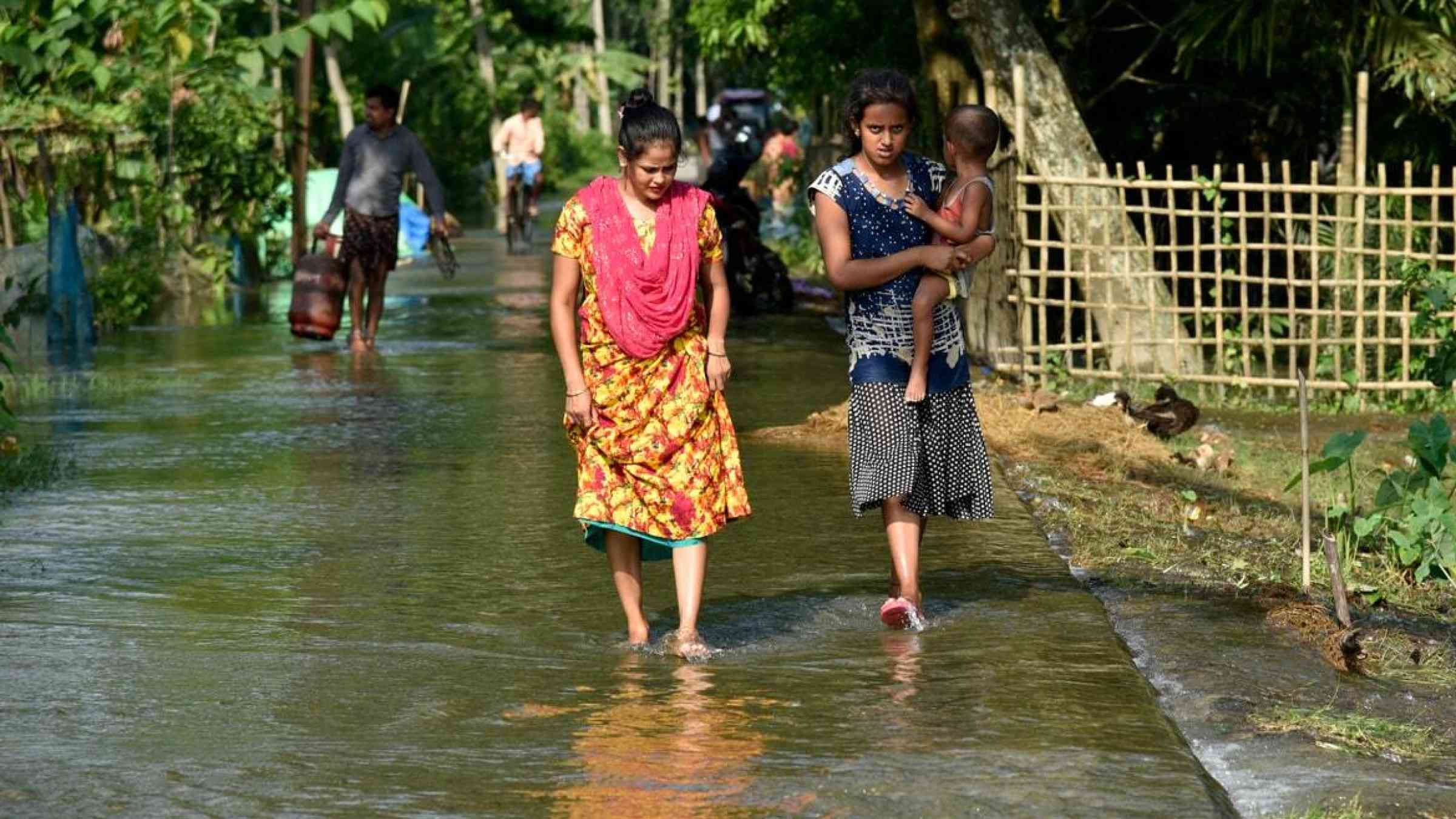 Women in Assam State, India wade through floods after heavy downpour