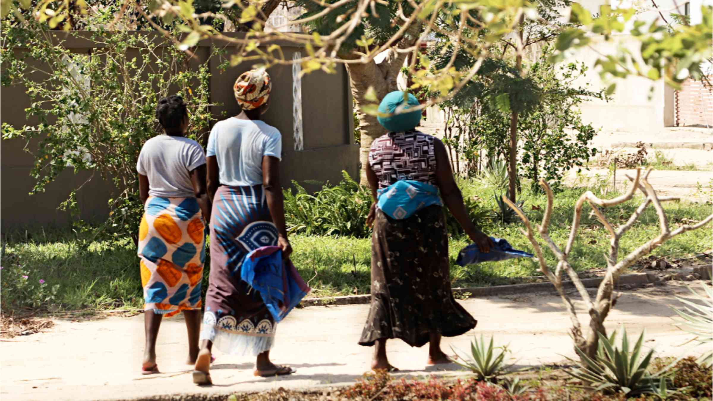 This image shows three women walking throught a green environment in the city of Beira in Mozambique.