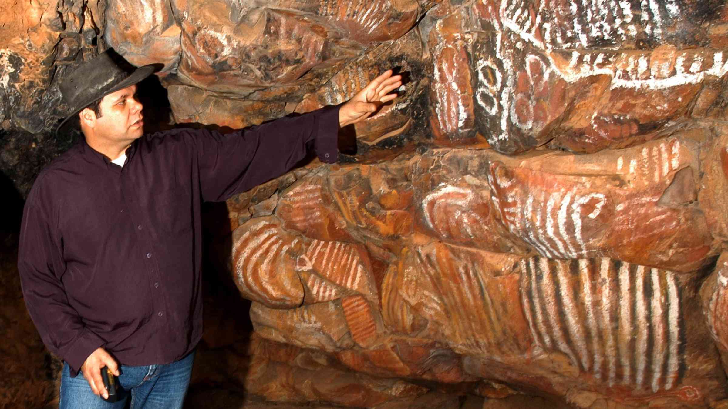 This image shows two people inspecting indigenous rock art in Australia that is threatened by climate change.
