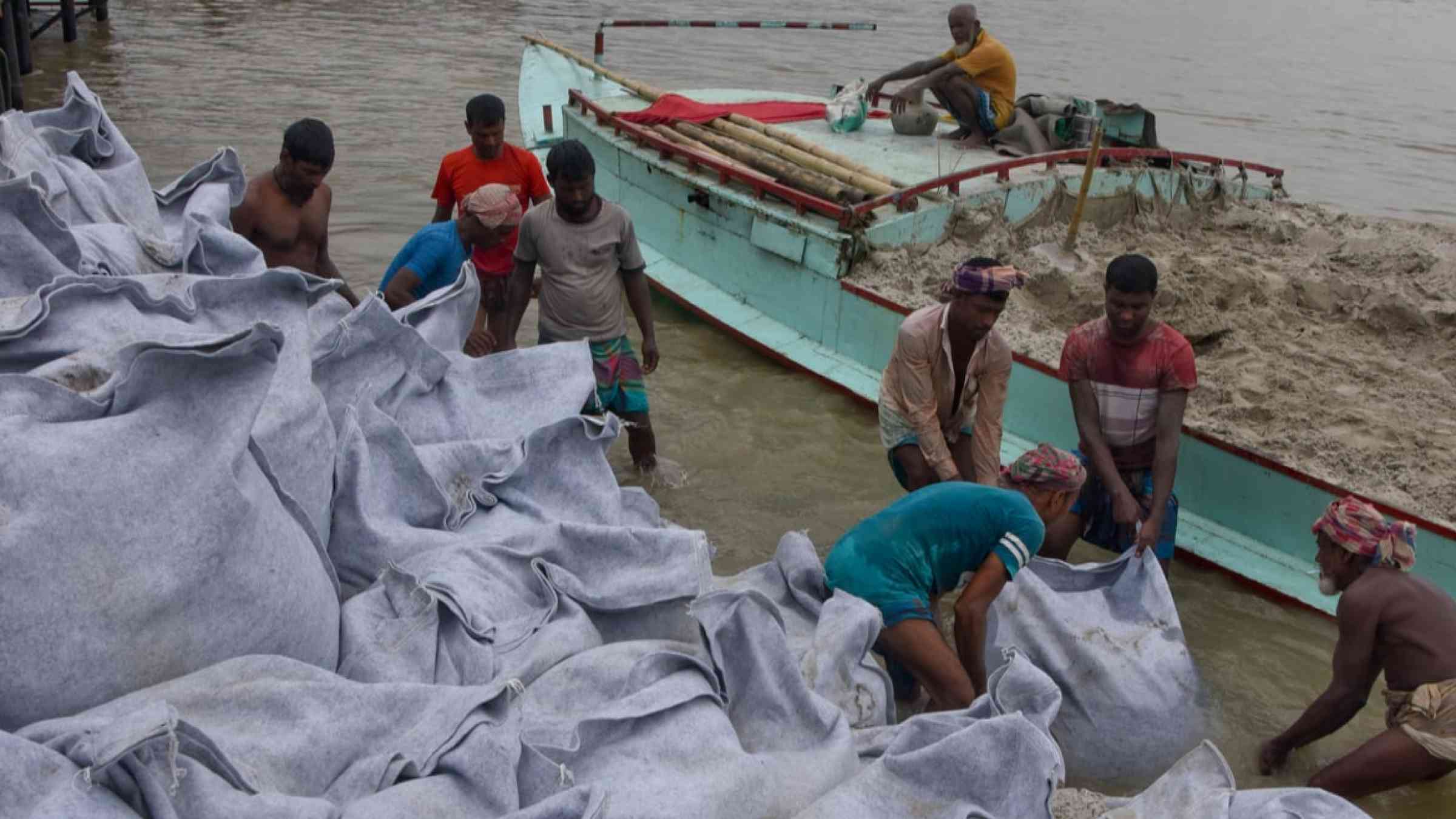 Workers prepare sandbags to repair the embankment near Dhaka, in Bangladesh (2020).