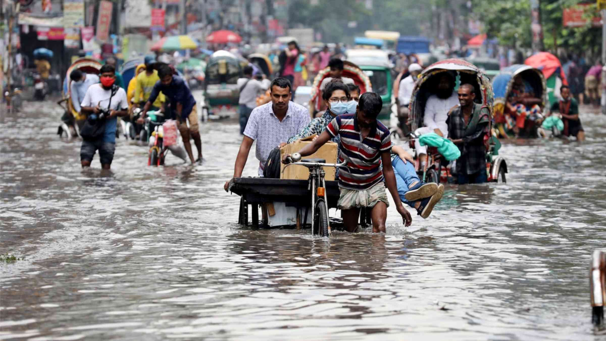 Vehicles try to drive through a flooded street in Dhaka, Bangladesh (2020)