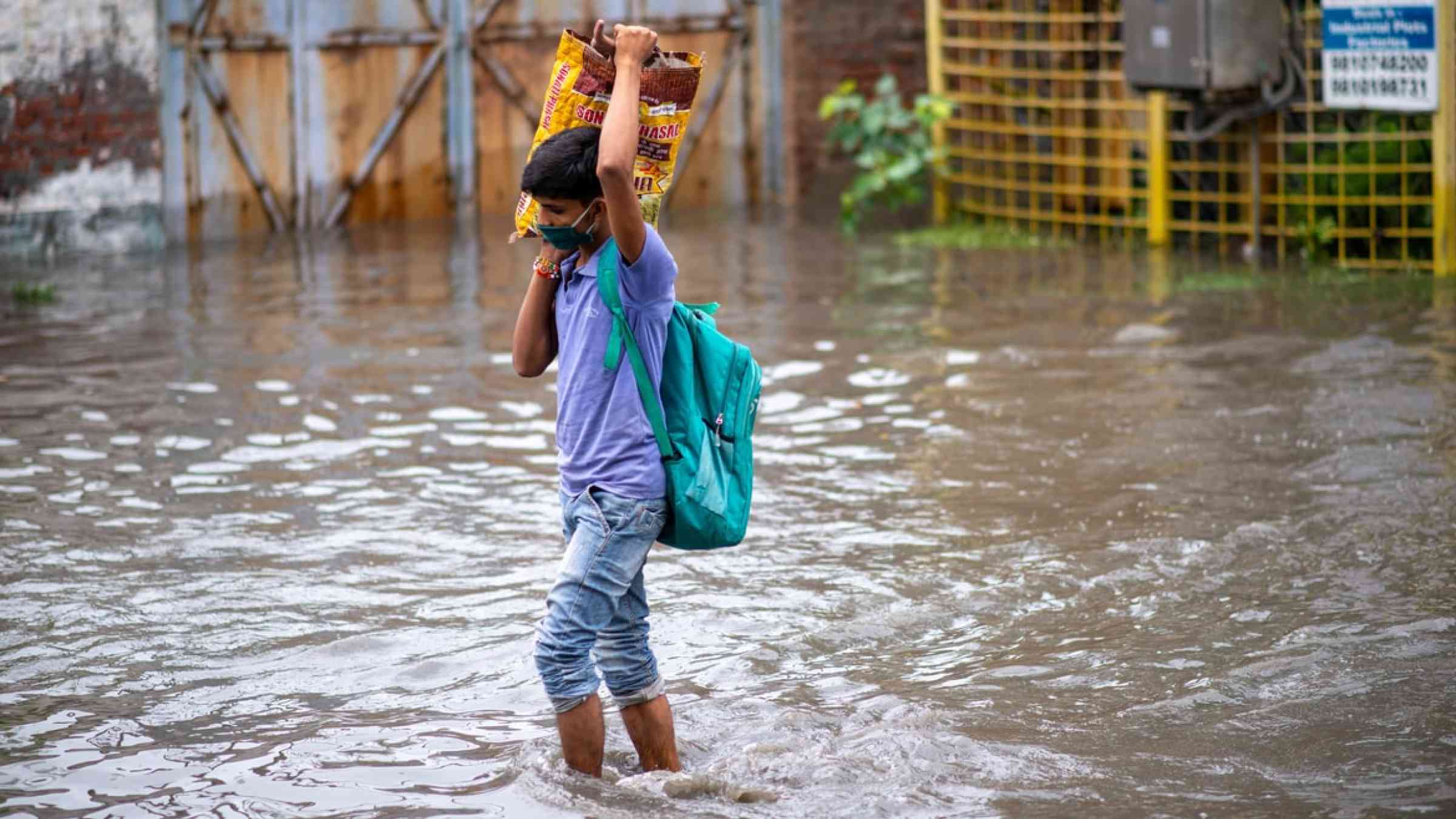 A young man walking through a flooded street in Ghaziabad, Uttar Pradesh, India (2021)