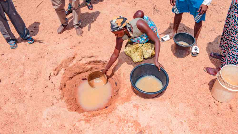 African woman fetching unclean and contaminated water from a pond for their daily consumption.