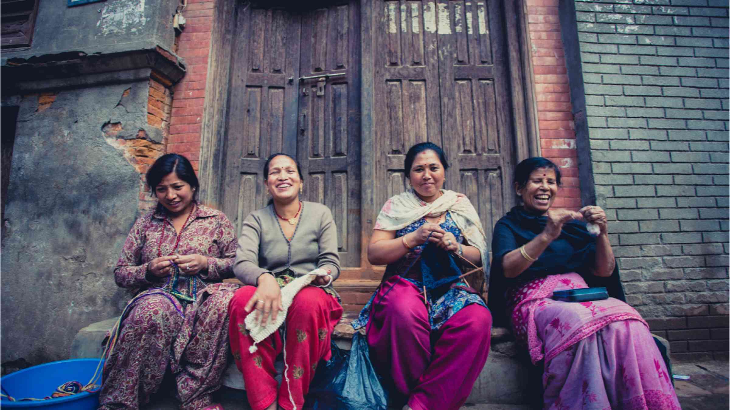  group of women in Bhaktapur smiling and working in the street. 