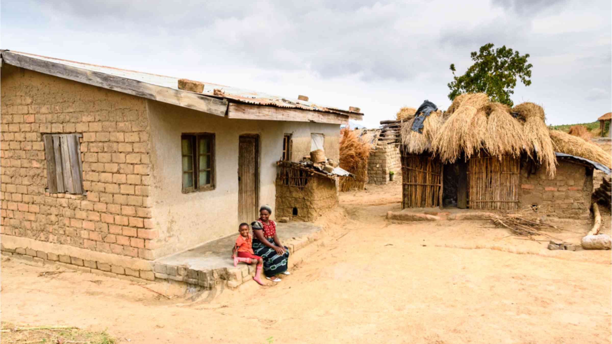 This image shows a mother with her child sitting in front of their house in Malawi. 