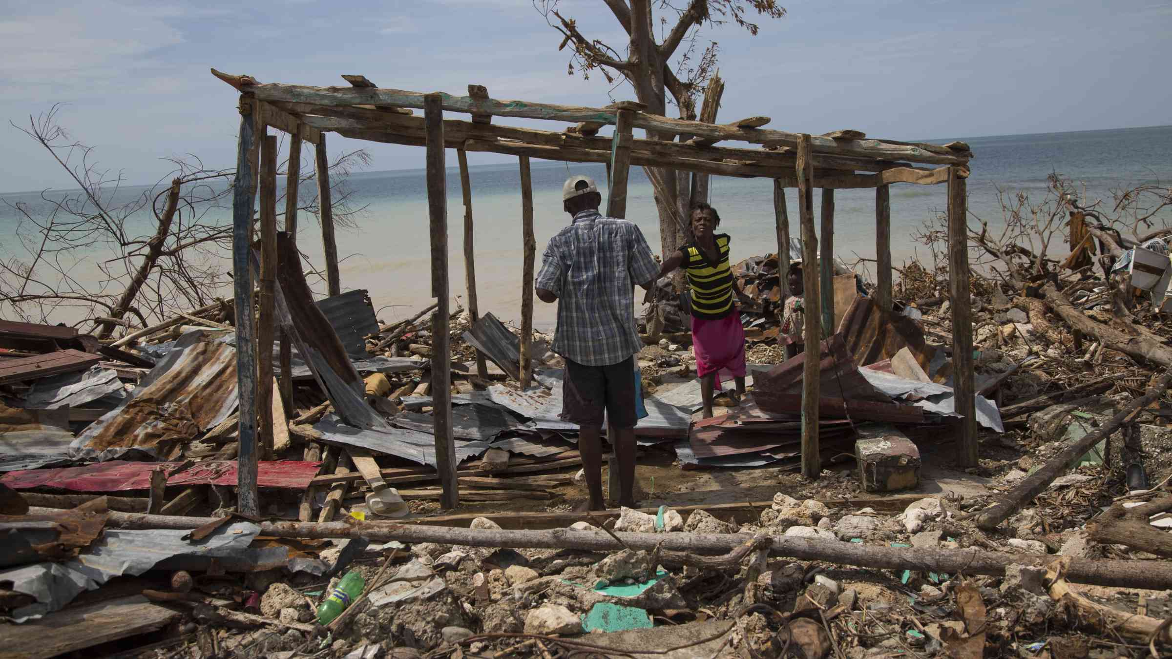 People in a destroyed house following Hurricane Matthew in Roche a Bateux, Haiti in October 2016.