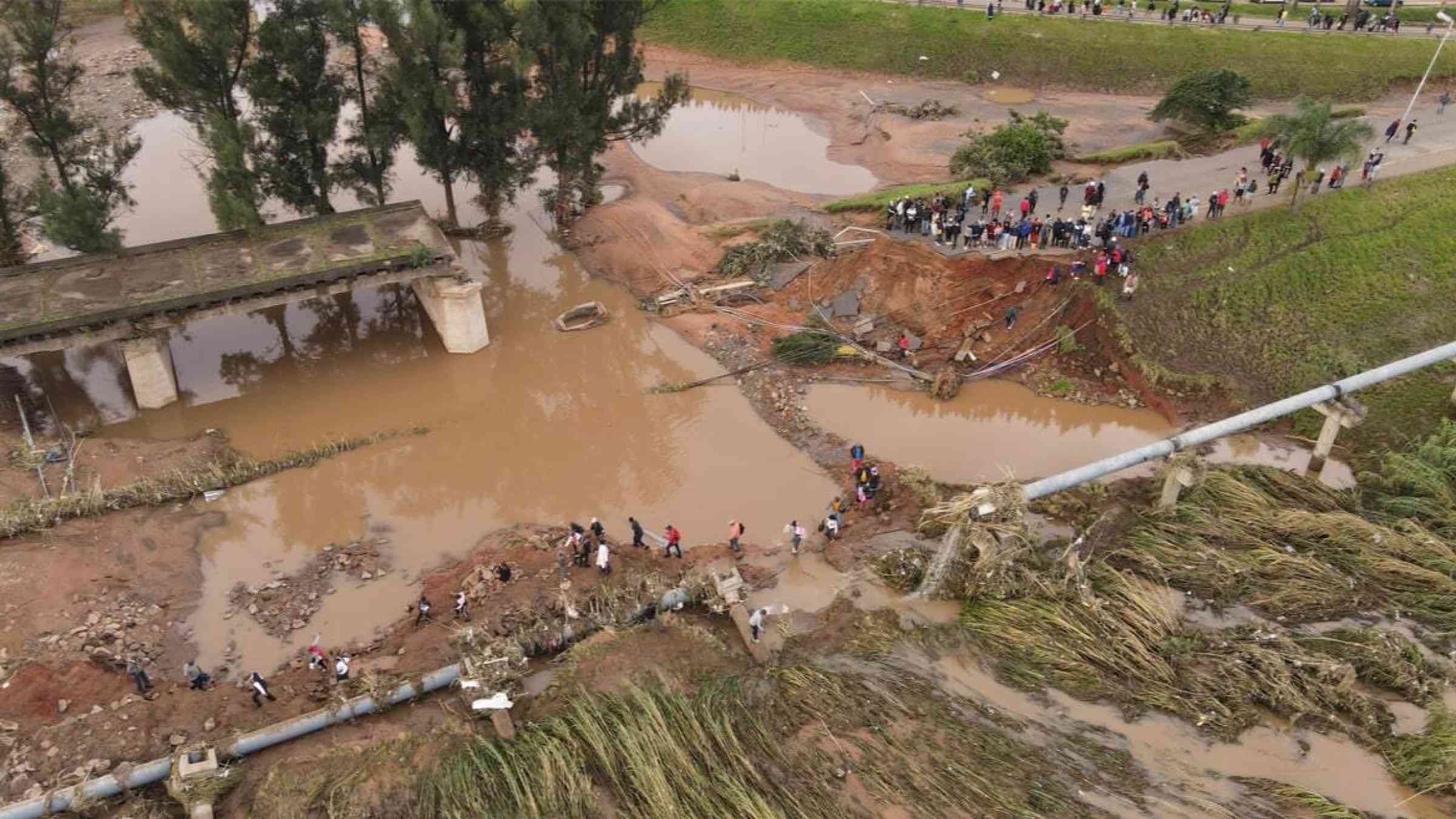 Workers return to a damaged road after floods in Durban