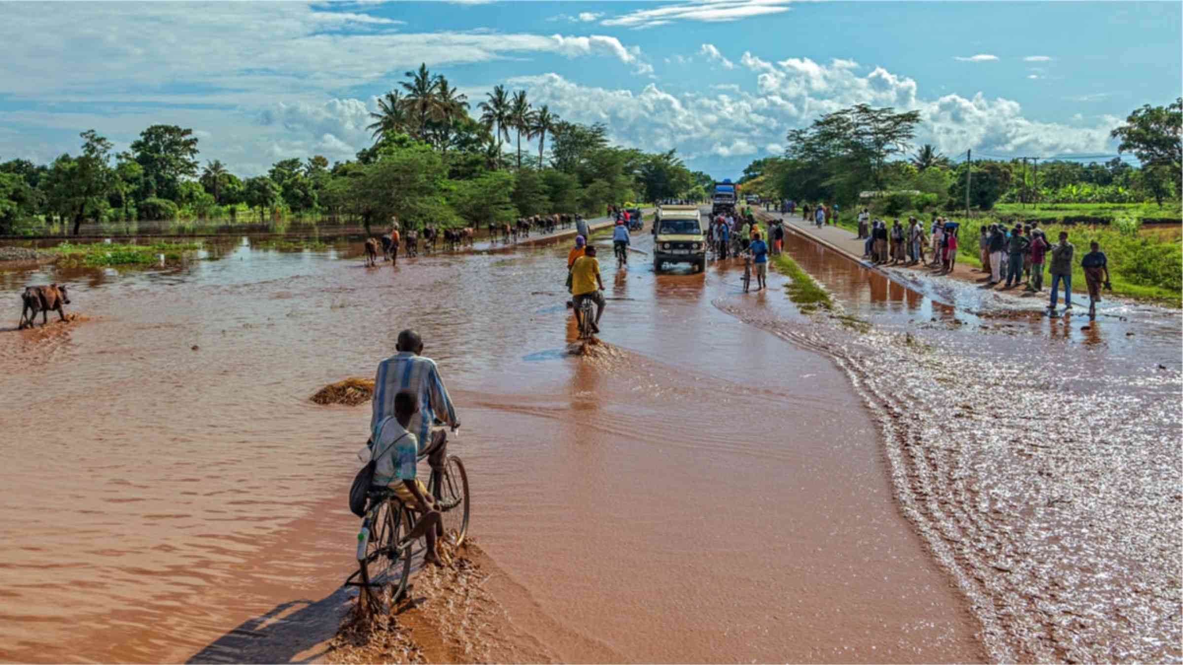 An African man biking through flooded streets.