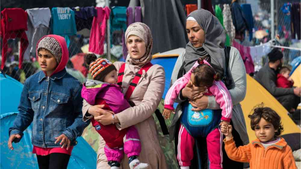 Two Syrian women walking through the streets with their four children.