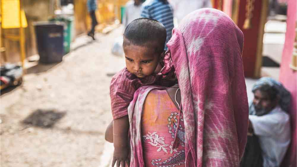 An Indian woman carrying her small child through the heated streets.