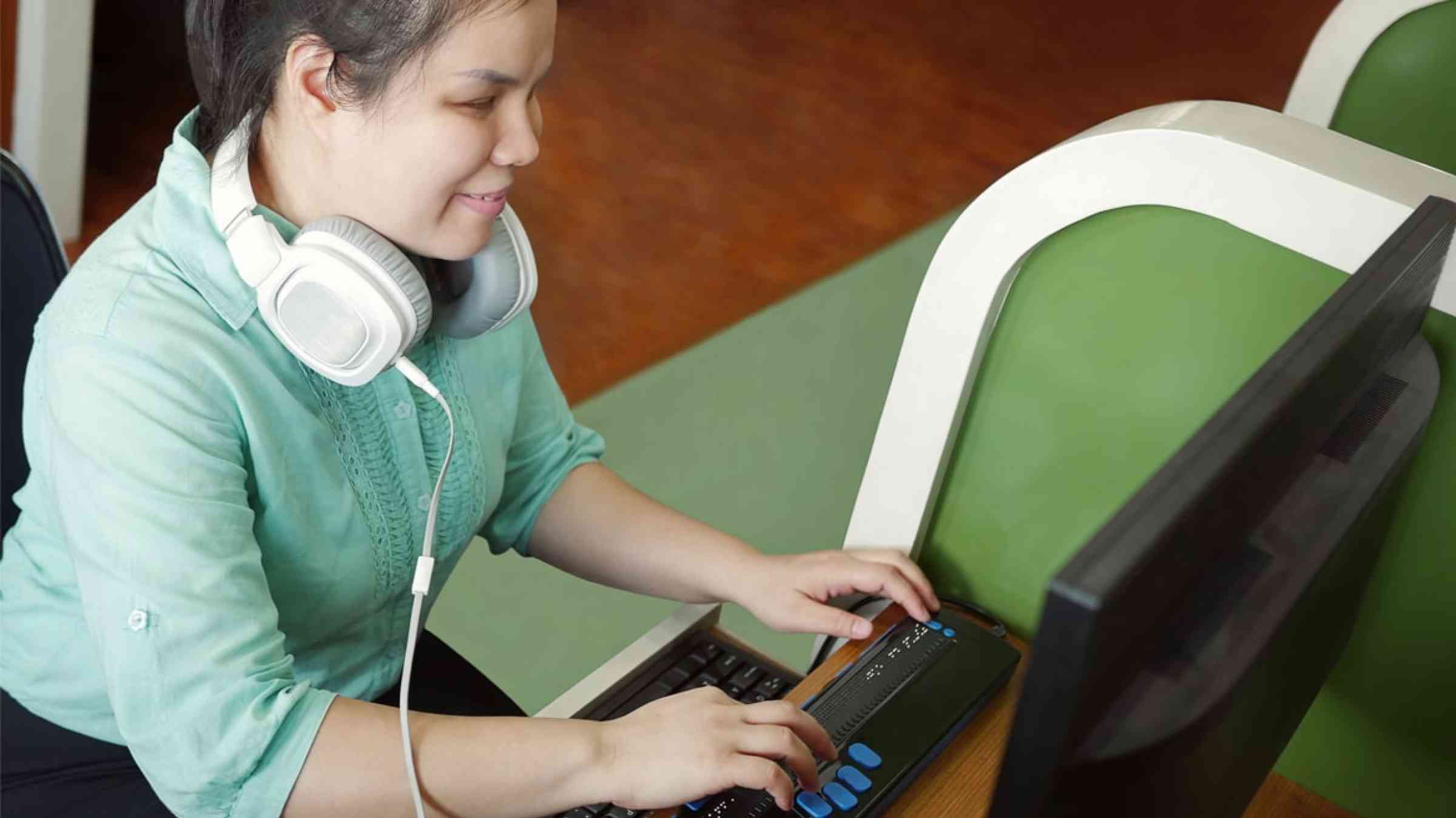 Young visually impaired woman with a headphone using a computer