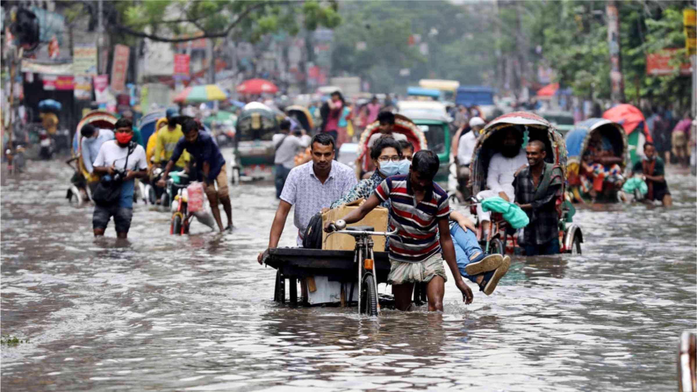 Riksha drivers walking through the flooded streets in Bangladesh in 2020.
