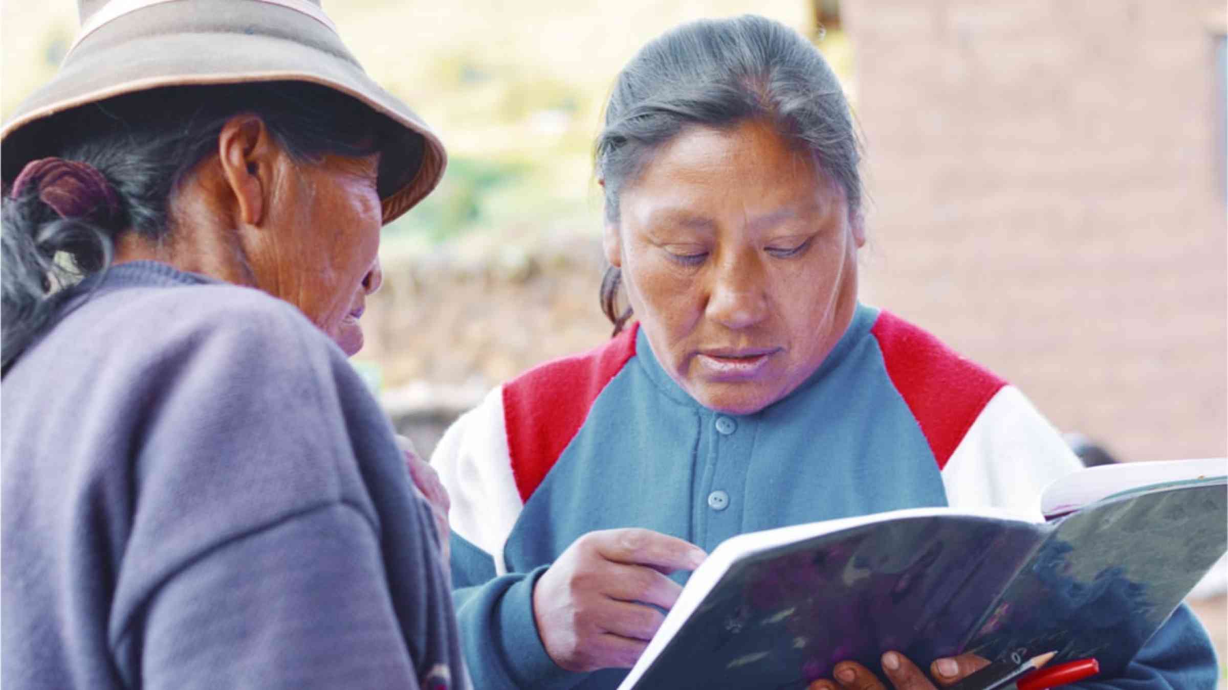Two indigenous women looking at a book.