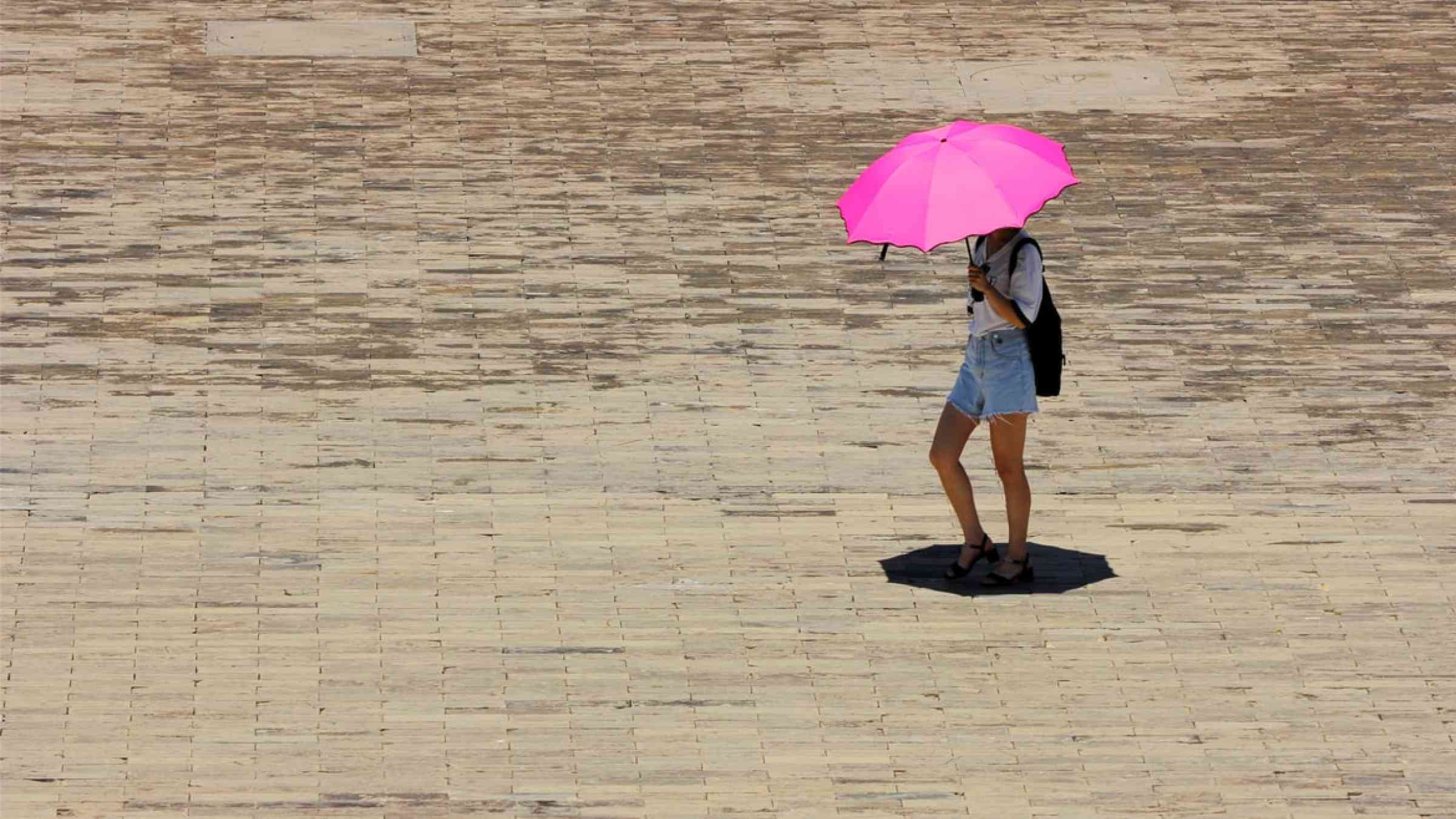 Person holding an umbrella during a hot day in a square